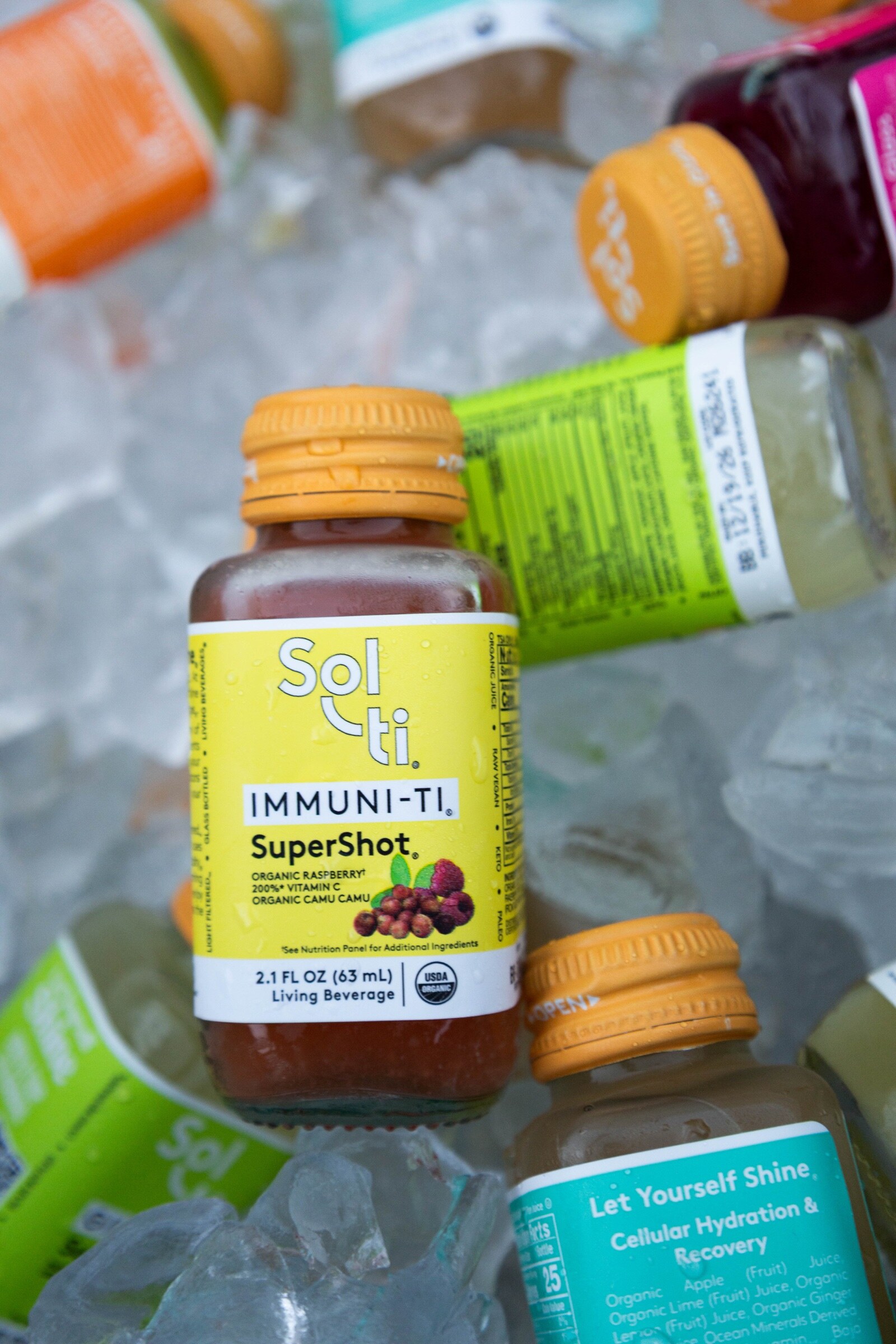 A Sol-ti Immuni-Ti SuperShot bottle with an orange cap resting on ice among other Sol-ti bottles.