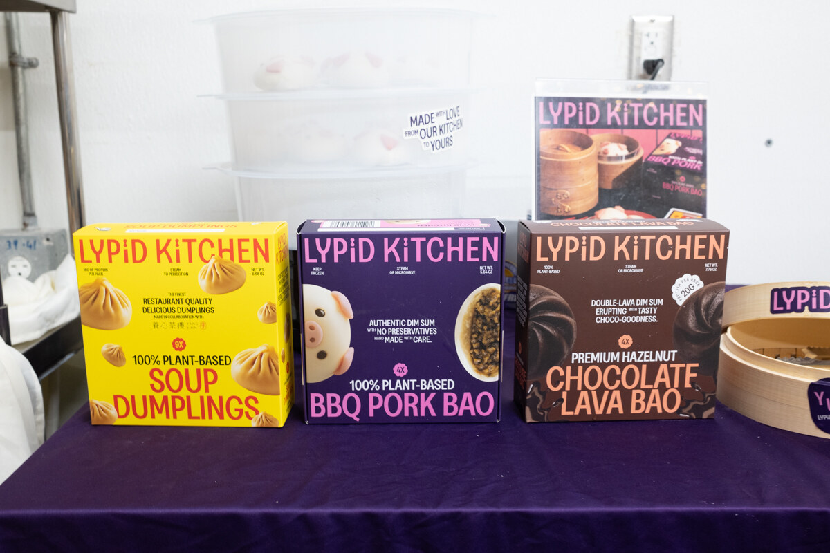 Boxes of Lypid Kitchen soup dumplings, BBQ pork bao and chocolate lava bao on a purple tablecloth.
