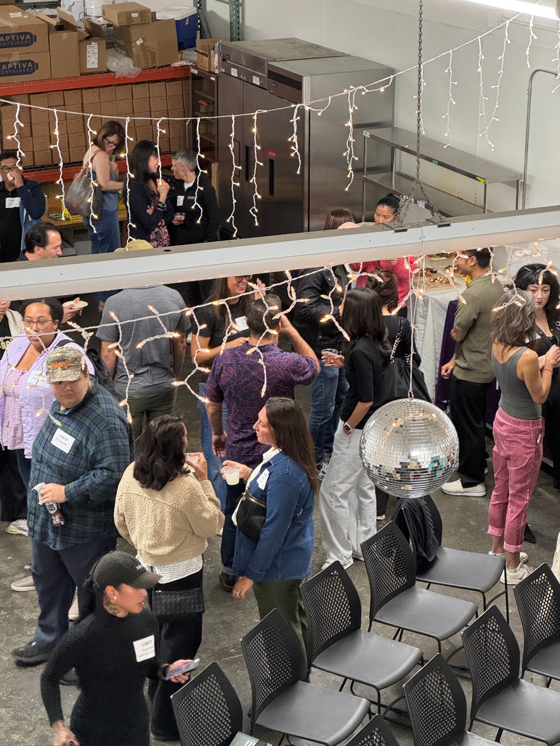 View from above of a crowded warehouse room with a disco ball and rows of chairs.