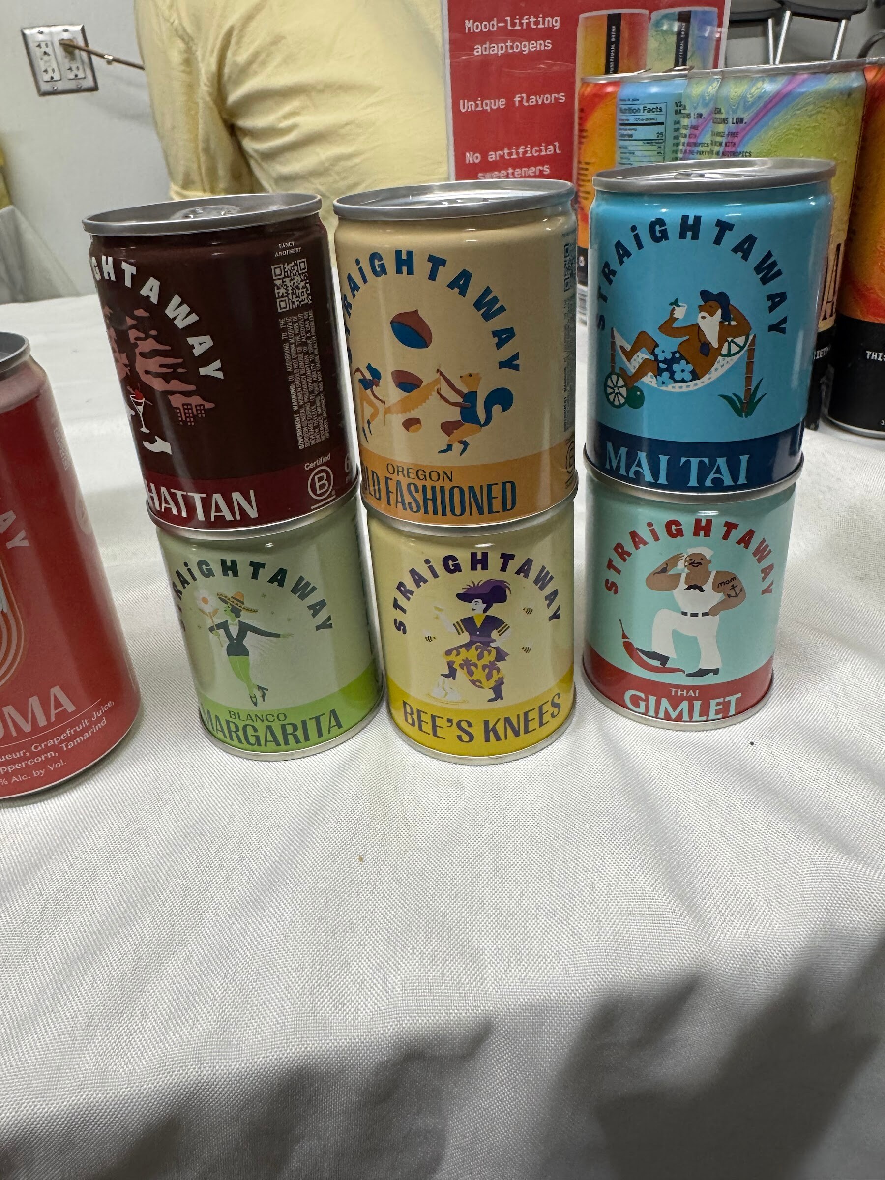 Stacked cans of Straightaway cocktails including Manhattan, Old Fashioned, Margarita and Gimlet.
