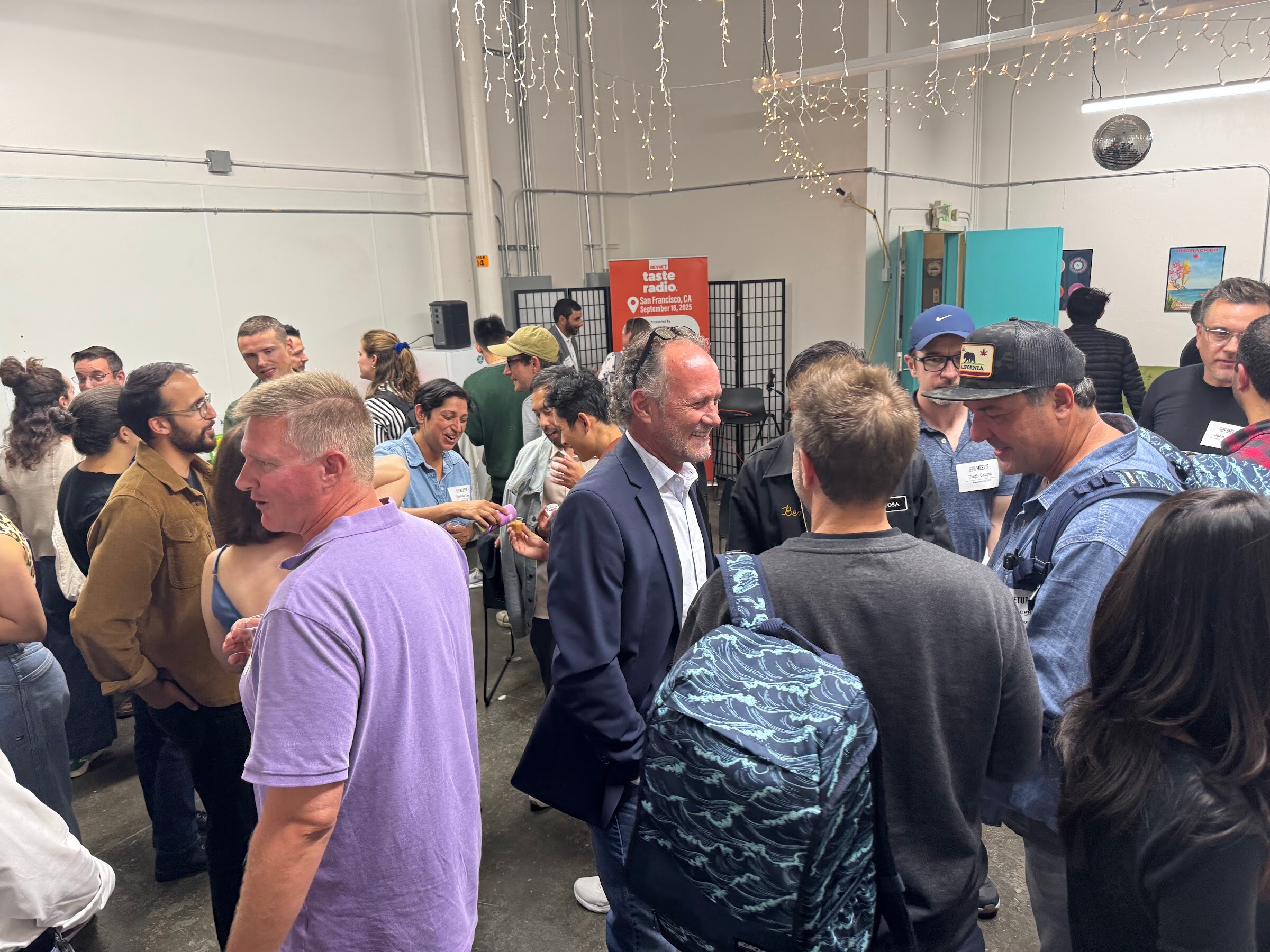 Group of attendees talking in a warehouse room with name badges.