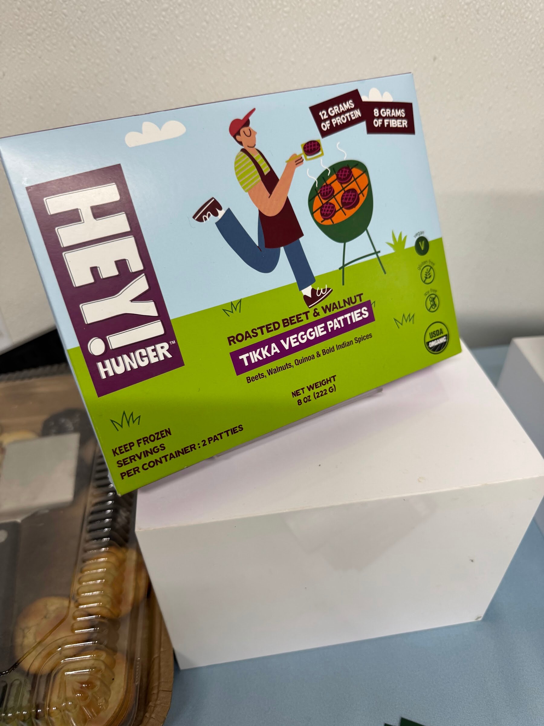 Boxes of HEY! Hunger roasted beet and walnut tikka veggie patties on white risers.
