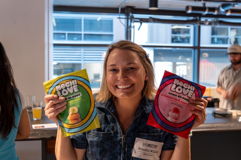 Smiling woman holds up two bags of Mochi Love Mini Clouds.