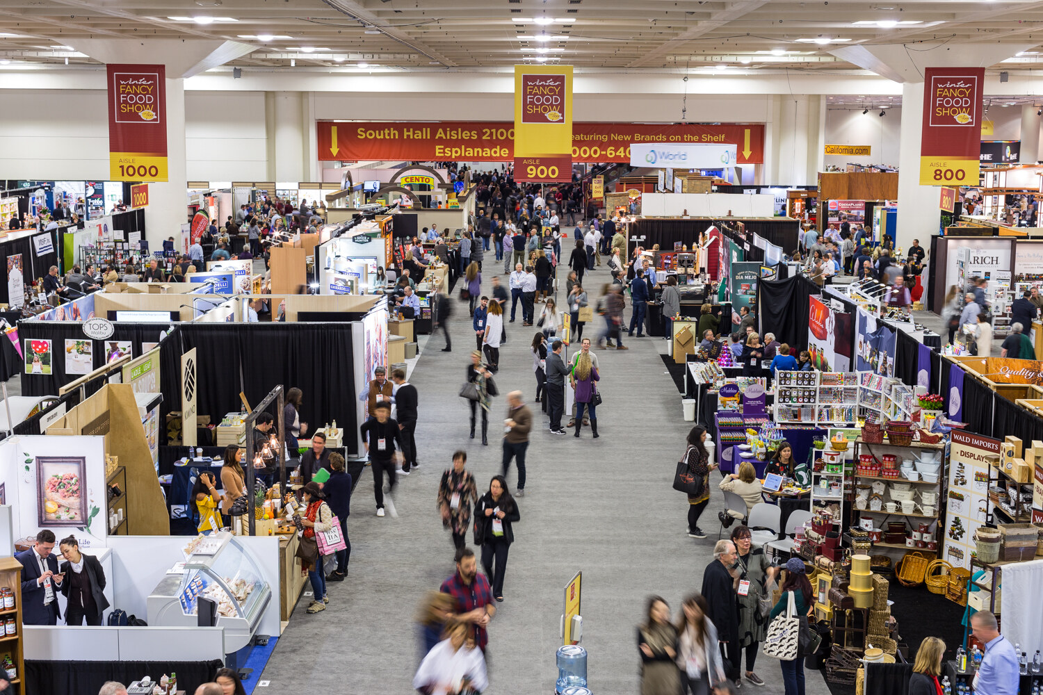 High-angle view of a crowded exhibit hall with banners and booths.