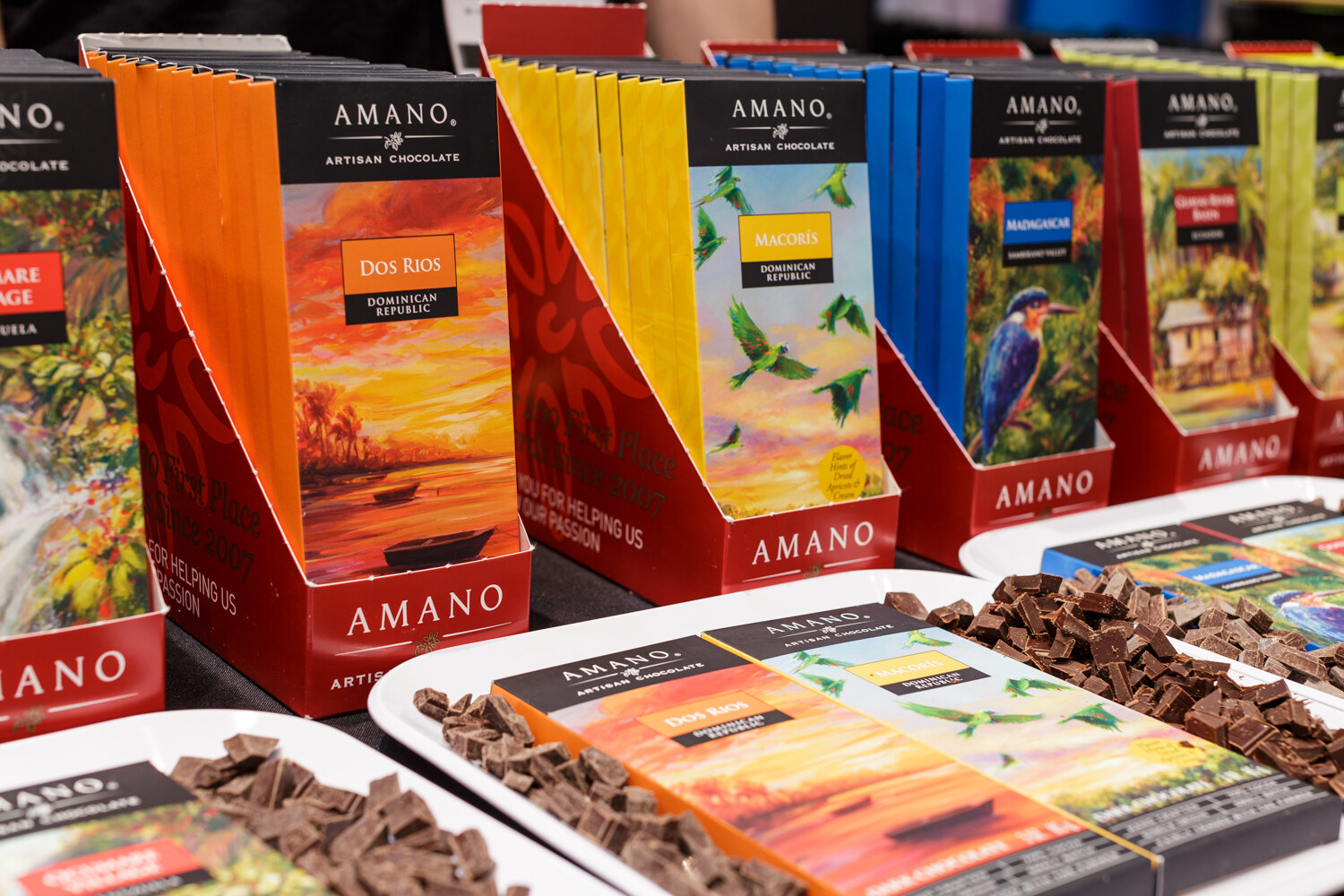 Display of illustrated Amano chocolate bars beside trays of chocolate chunks.