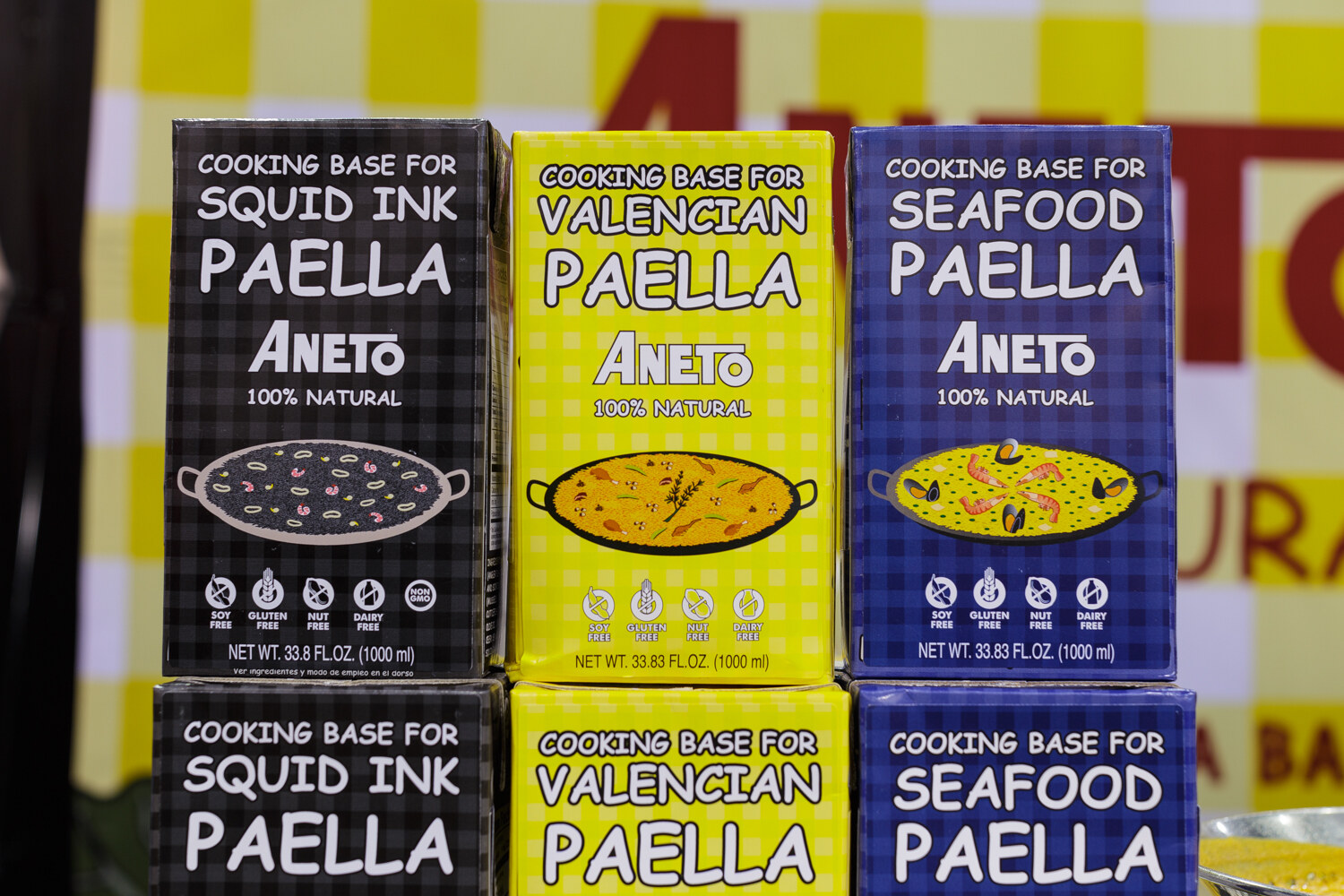 Boxes of paella cooking base stacked on a shelf.