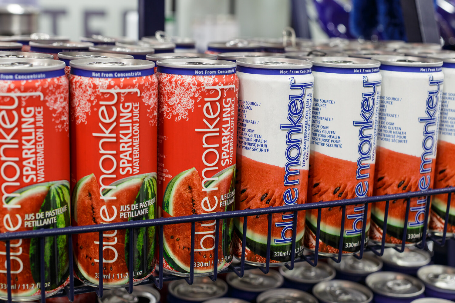 Cans of Blue Monkey sparkling watermelon juice in a wire rack.