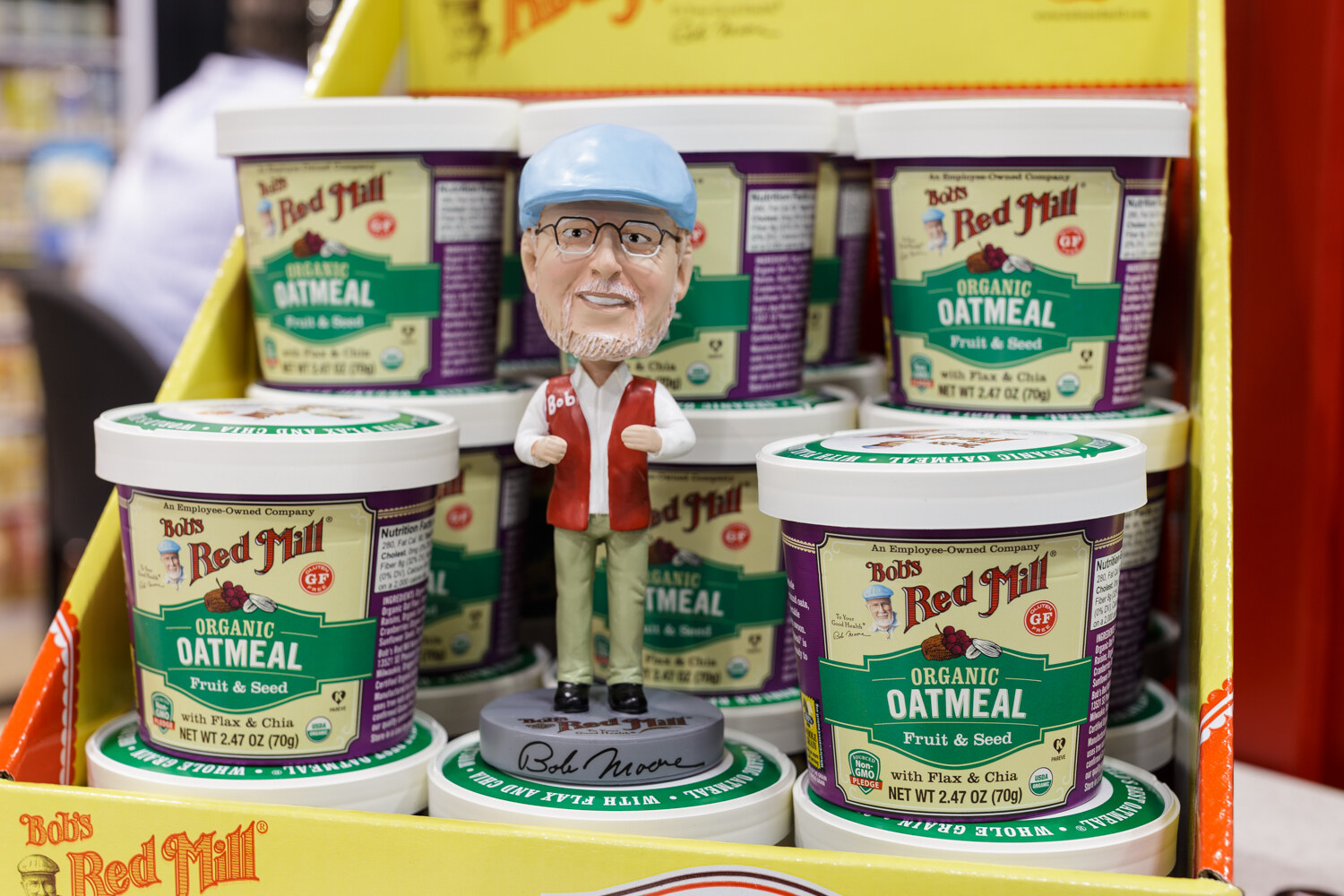 Oatmeal cups and a founder bobblehead on a yellow display.