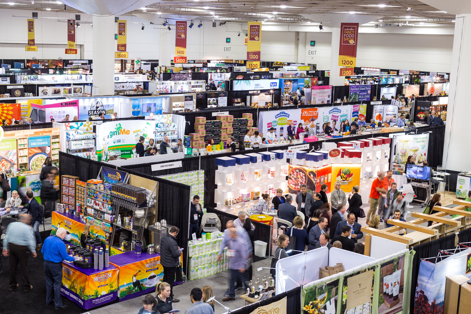 Overhead view of exhibit hall booths with large crowds.