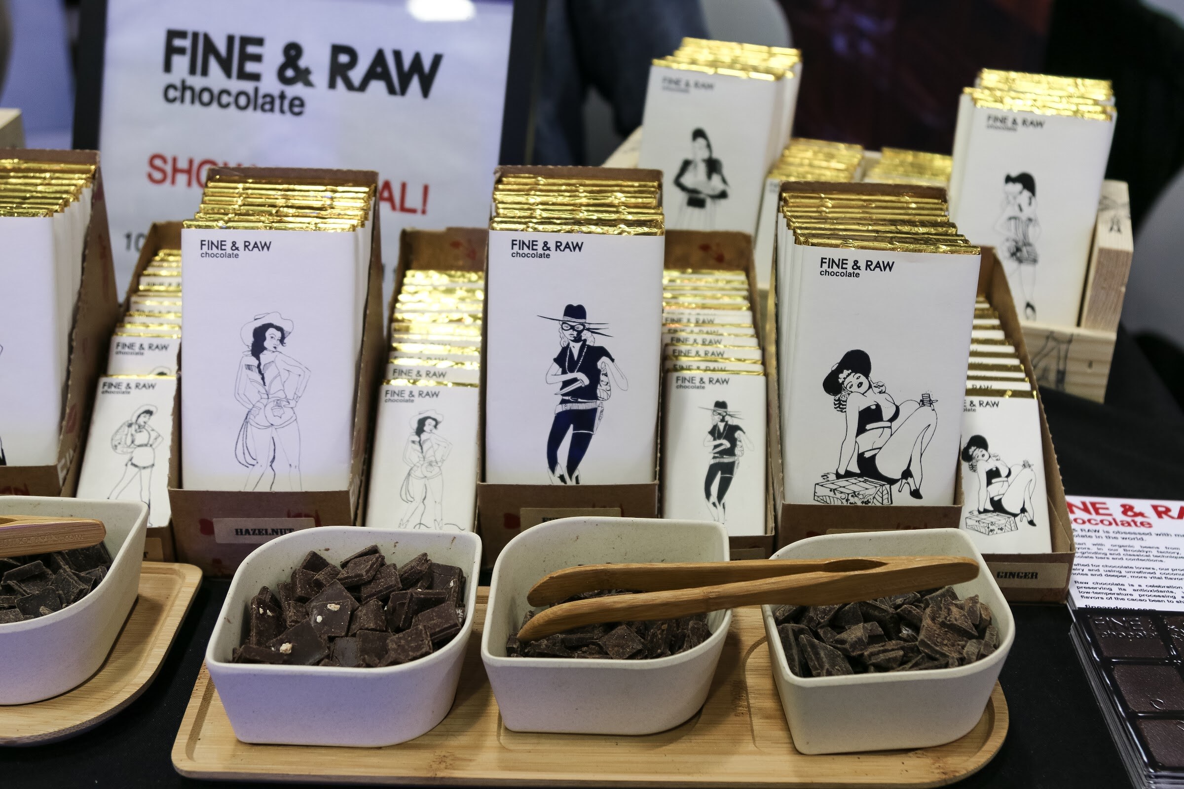 Boxes of Fine & Raw chocolate bars beside bowls of chocolate pieces.