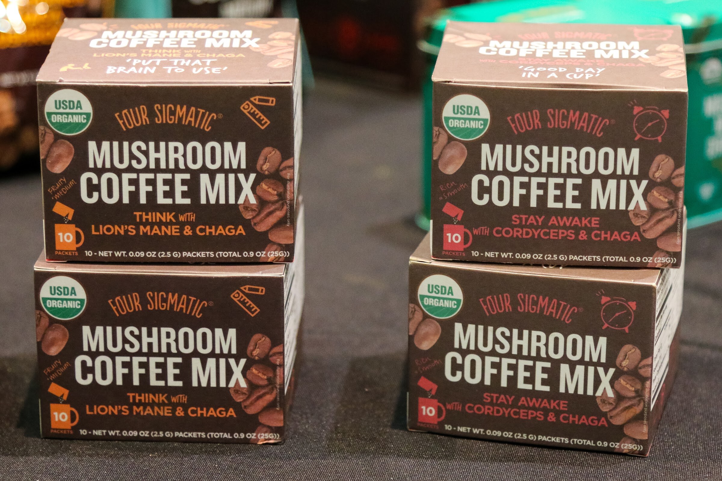 Packets and boxes of mushroom coffee on a booth shelf.