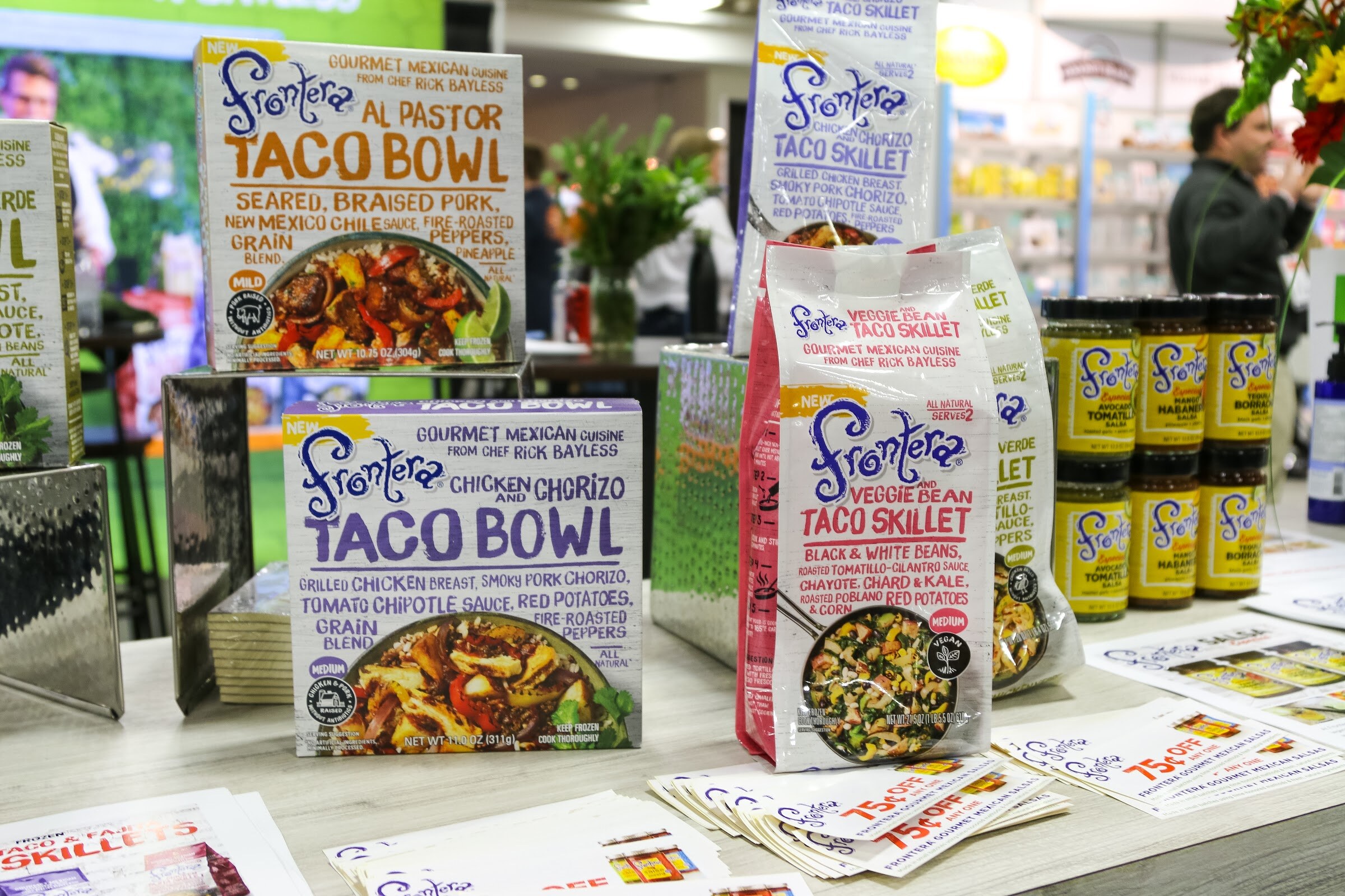 Boxes of Frontera taco bowls and taco skillets with sauce jars on a table.