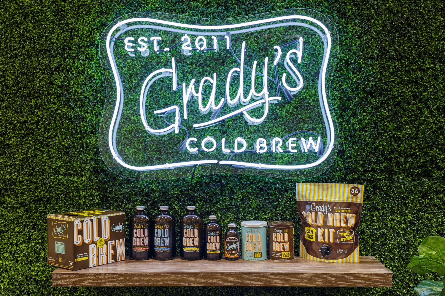 Neon Grady's Cold Brew sign over bottles on a shelf.