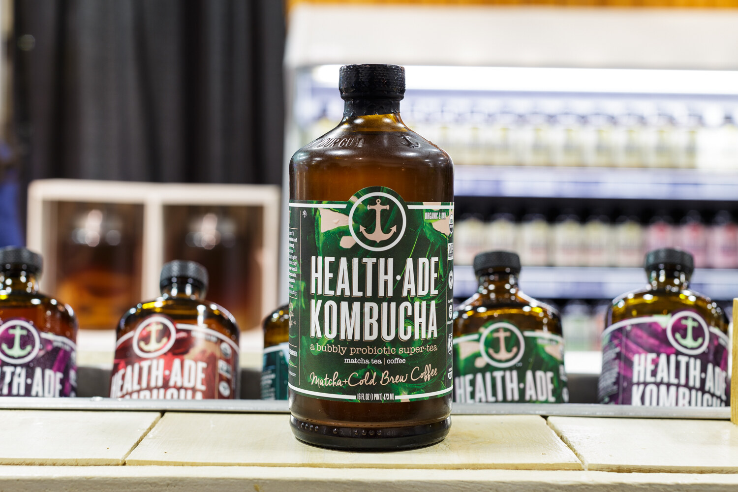 Bottles of kombucha with Health-Ade labels on a booth table.