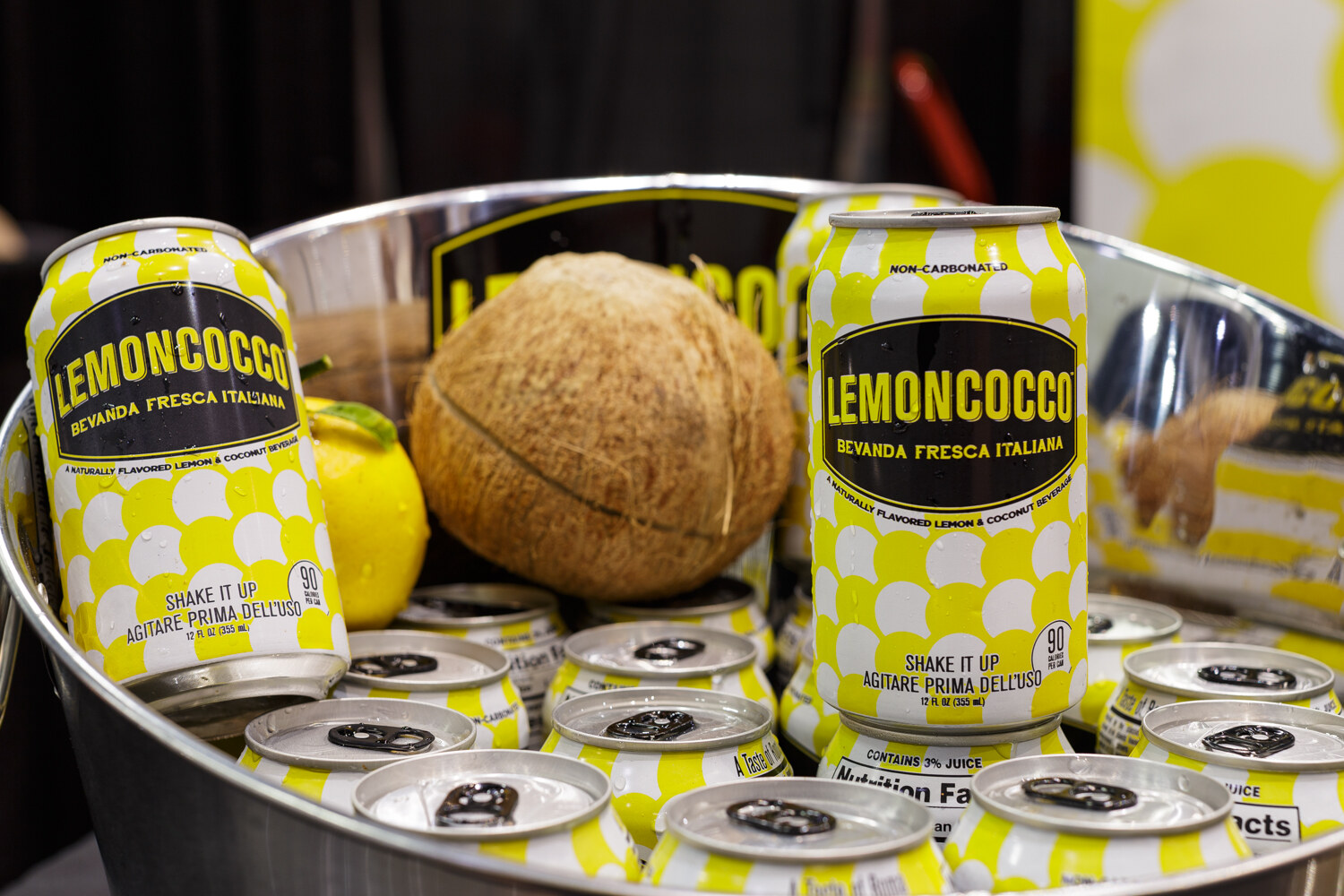 Cans of lemon-coconut drink in a bucket with a coconut and lemon.