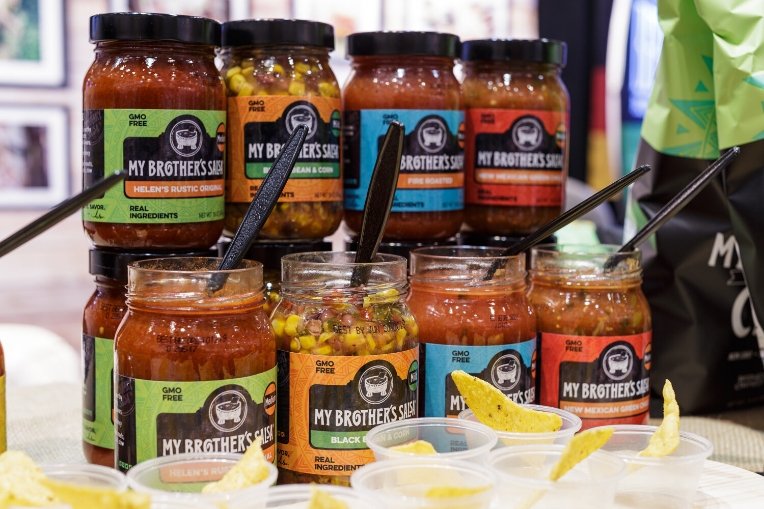 Jars of salsa in different colors on a shelf.