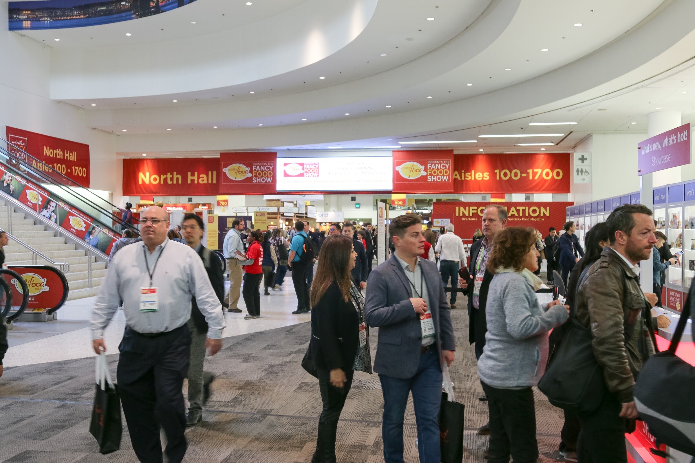 Crowd walking in the North Hall lobby with Fancy Food Show banners.