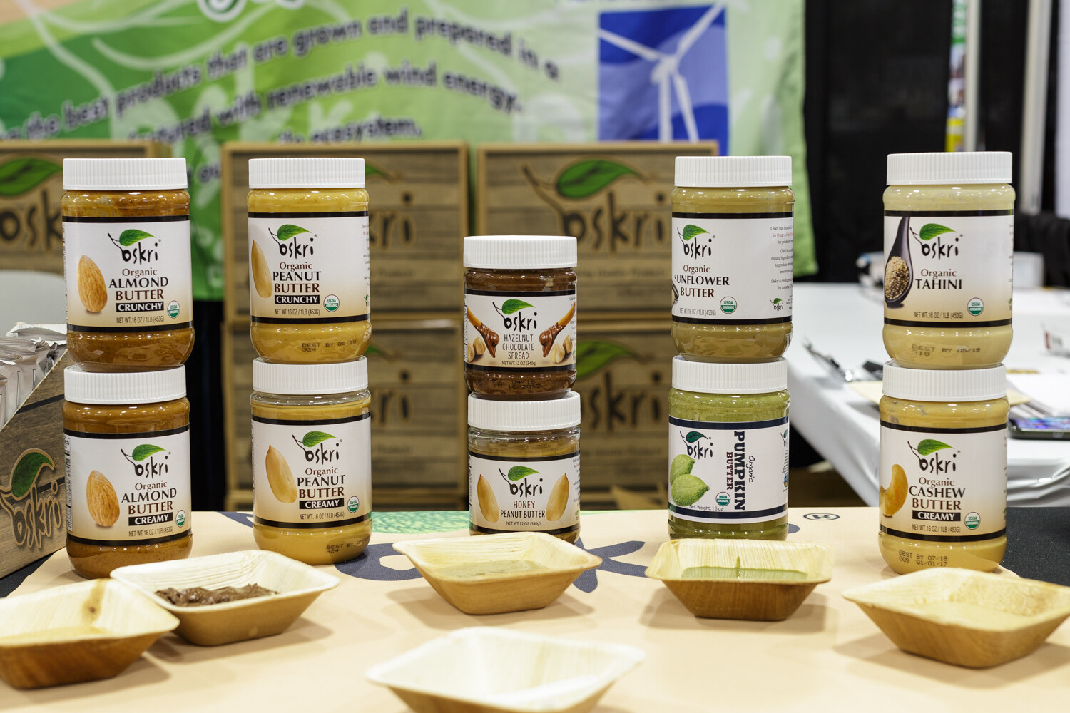 Jars of Oskri almond, peanut, sunflower and cashew butters beside small tasting bowls.