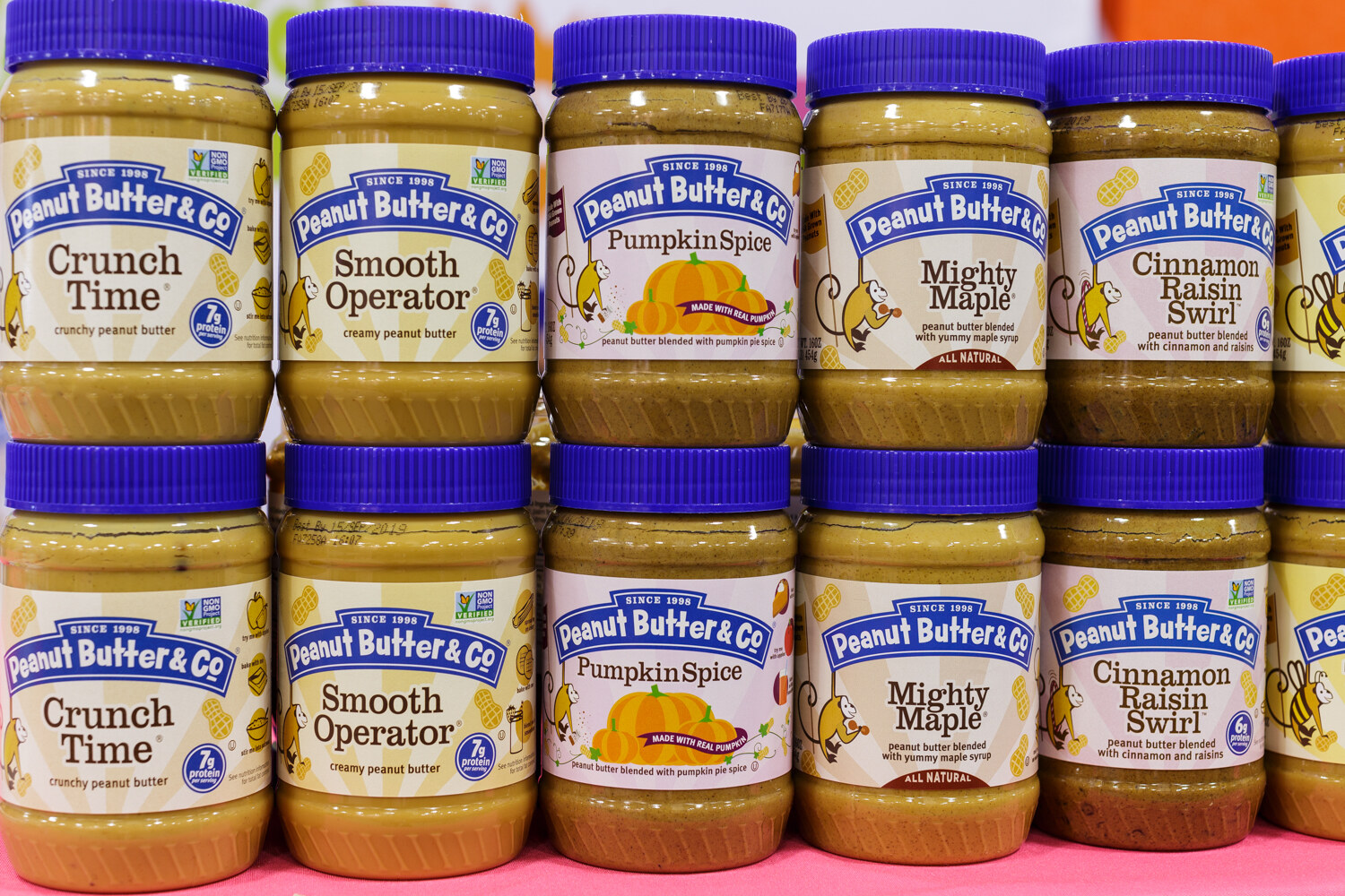 Stacked jars of peanut butter with colorful lids.