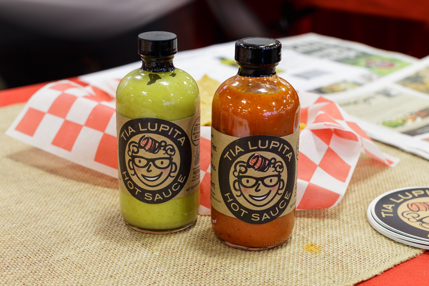 A green and an orange hot sauce bottle labeled Tia Lupita.