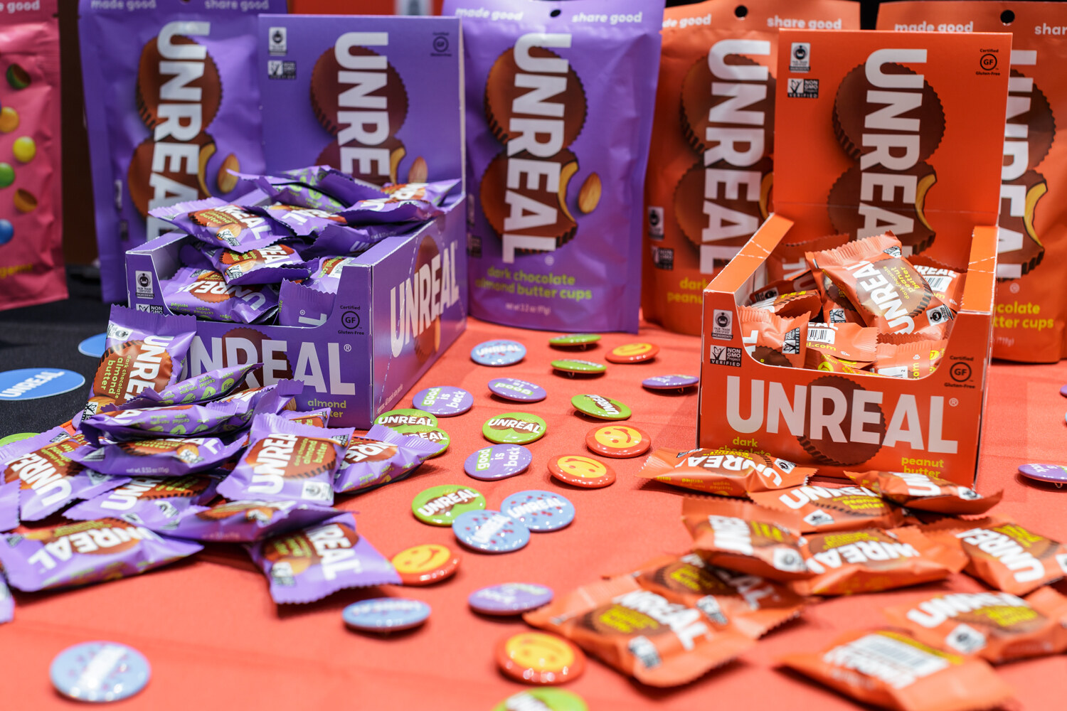 Boxes and bags of Unreal candy scattered across a red table with buttons.