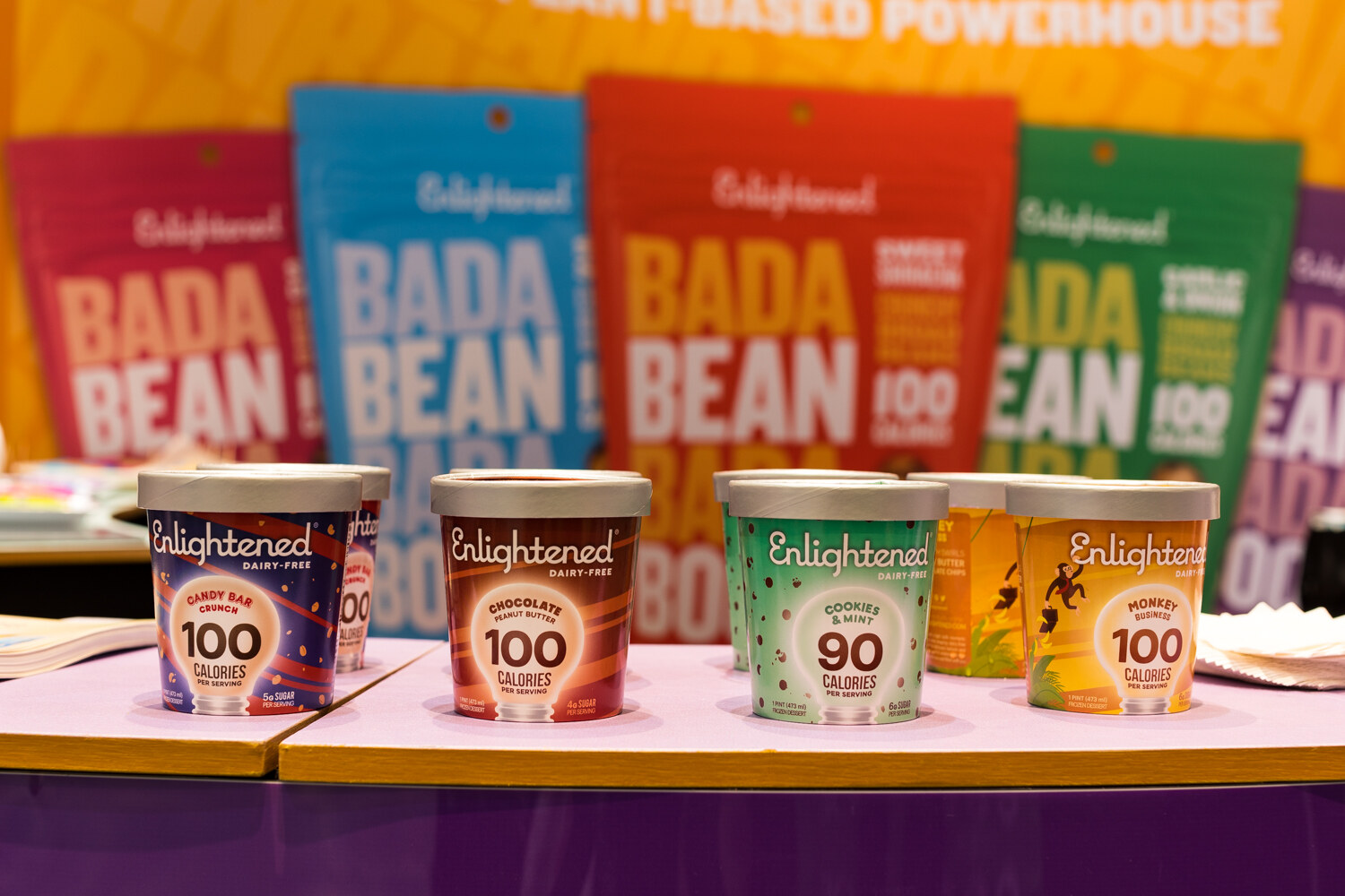 Photo of Enlightened ice cream pints and Bada Bean Bada Boom bags on a purple counter.