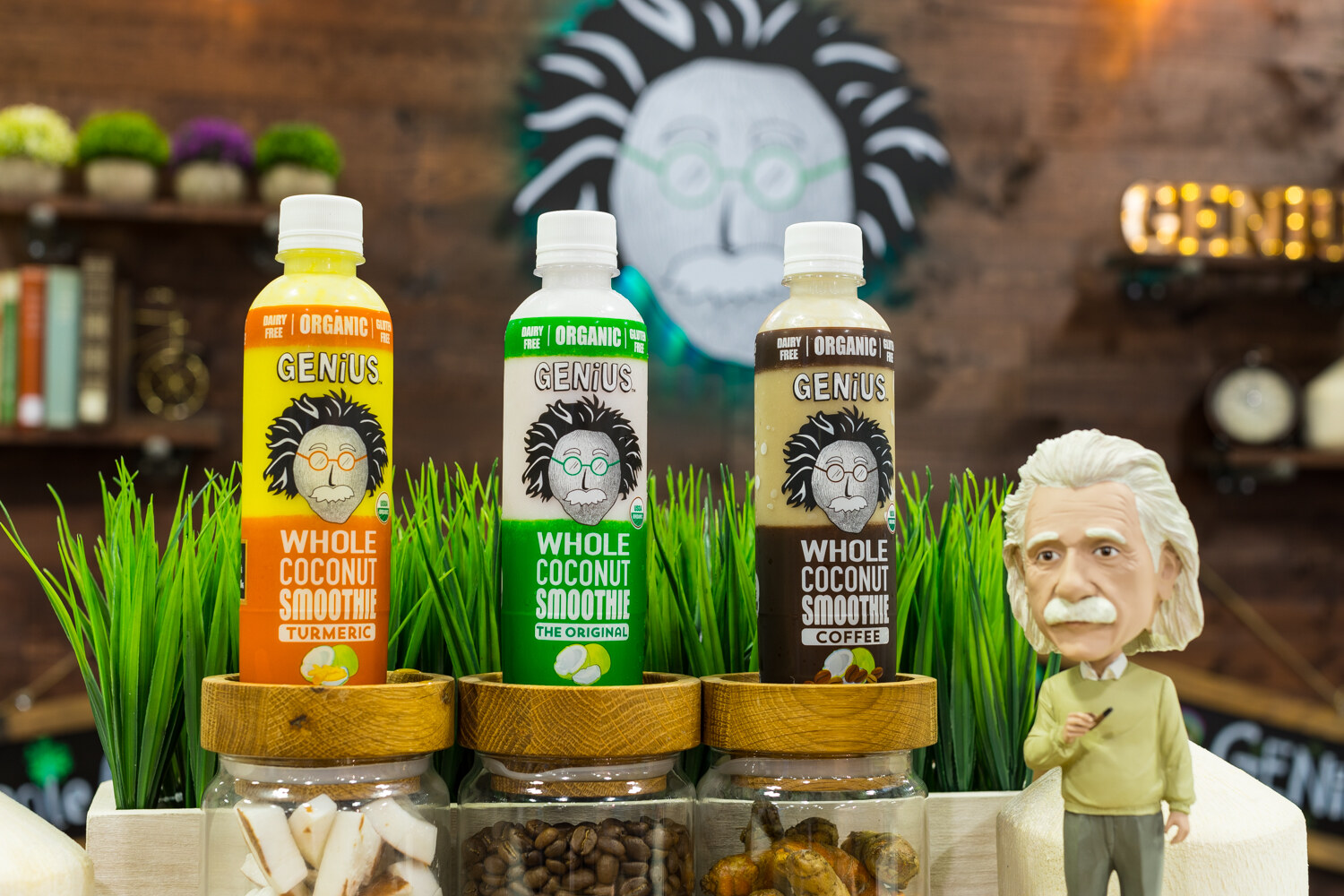 Photo of bottles of Genius organic whole coconut smoothie beside a small Einstein figurine.