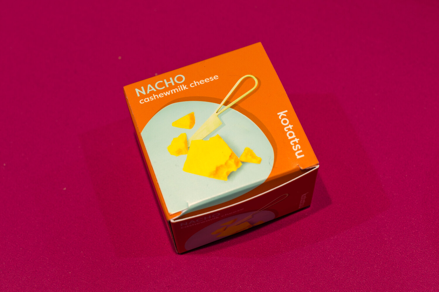 Photo of a Kotatsu nacho cashewmilk cheese box on a magenta cloth.