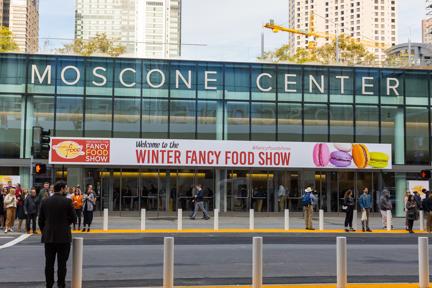 Photo of the Moscone Center entrance with a Winter Fancy Food Show banner and people on the sidewalk.