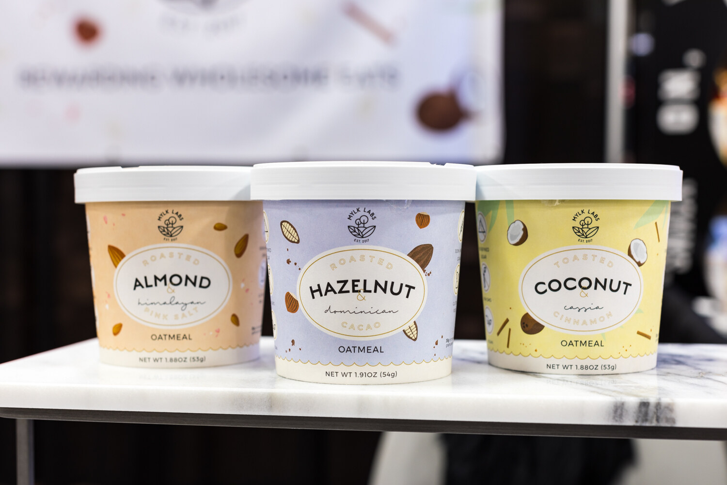 Photo of cups of almond, hazelnut and coconut oatmeal on a marble shelf.