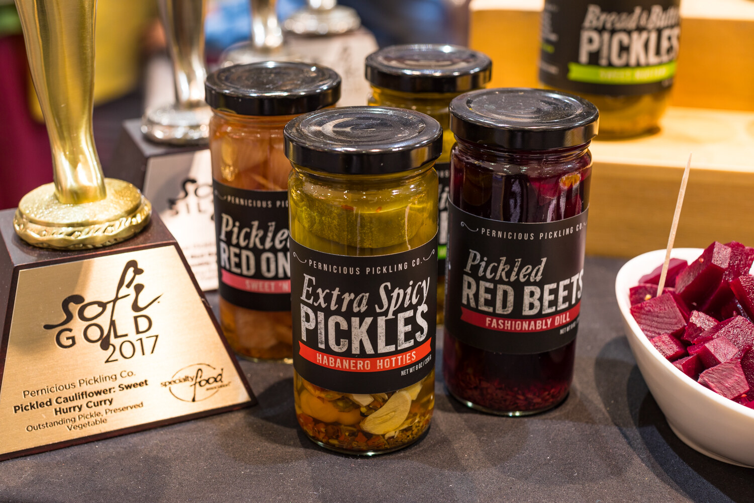 Photo of jars of Pernicious Pickling Co. pickles beside a sofi Gold 2017 trophy.