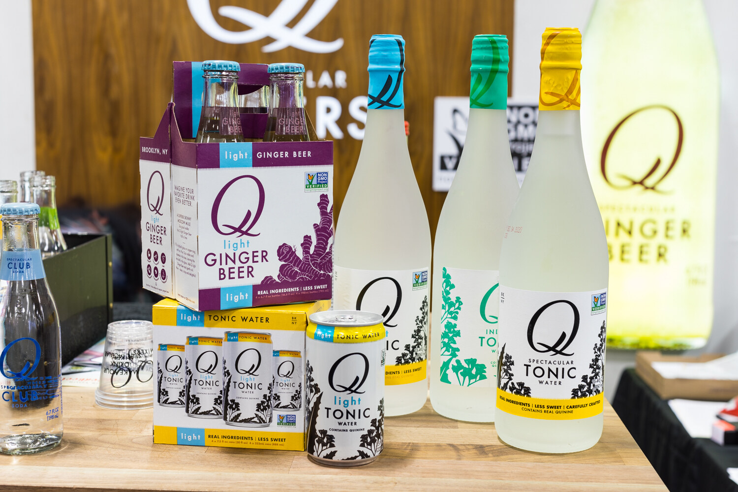 Photo of Q Mixers ginger beer, tonic and bottles on a wooden counter.