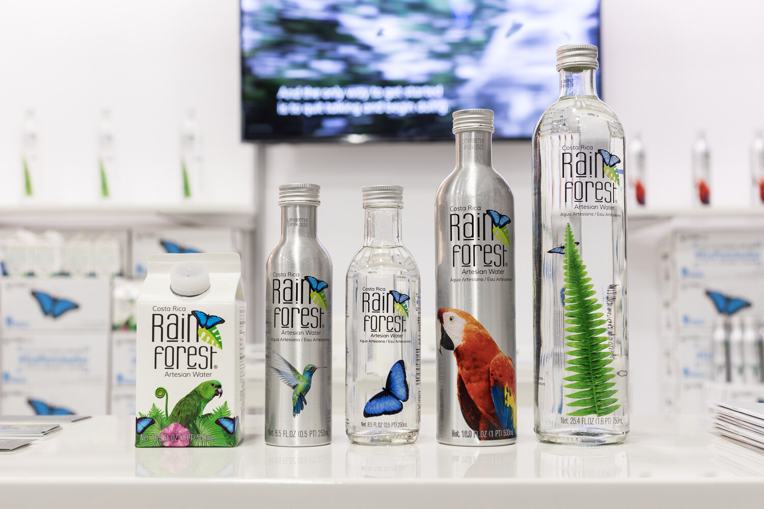 Photo of aluminum and glass bottles of Rain Forest water decorated with a macaw and butterflies.