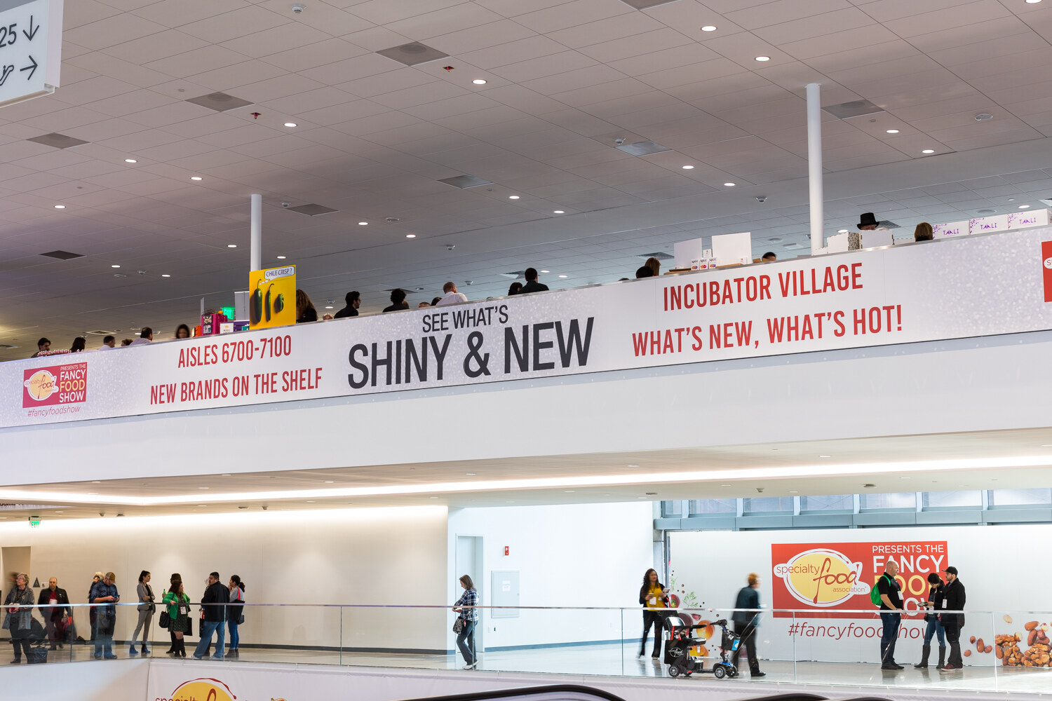 Photo of hanging banners reading Shiny and New, Incubator Village and New Brands on the Shelf above a concourse.