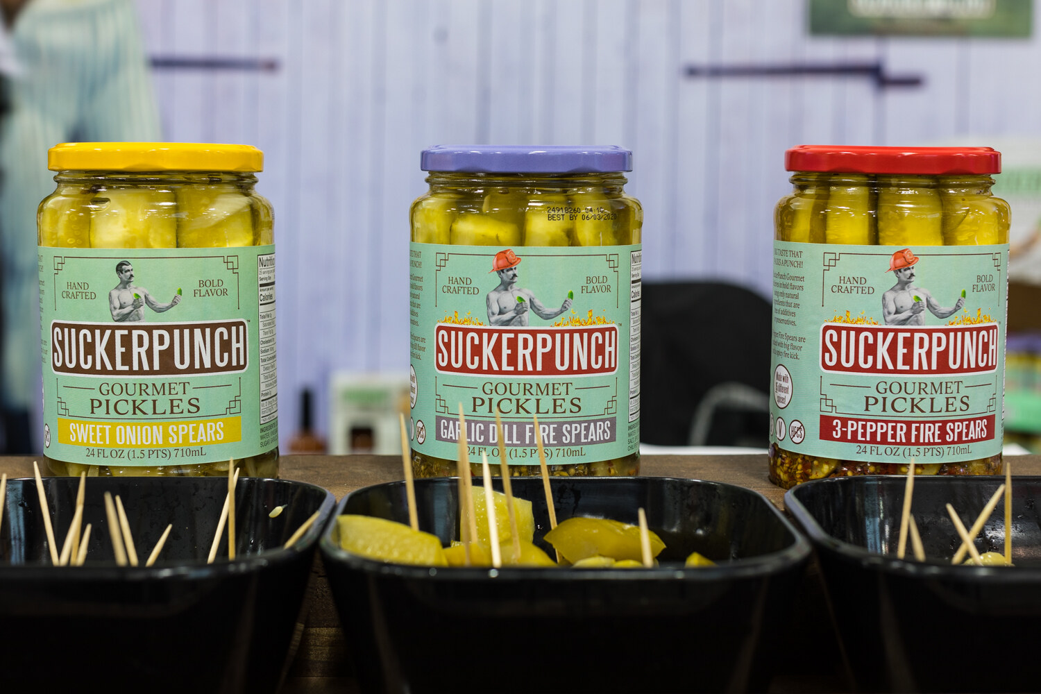 Photo of jars of Suckerpunch gourmet pickles in front of bins of samples.