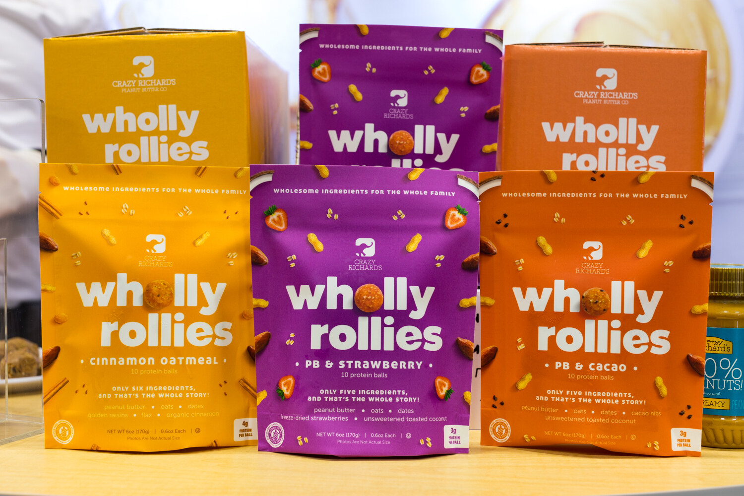 Photo of Wholly Rollies boxes and pouches in cinnamon oatmeal, PB and strawberry, and PB and cacao.