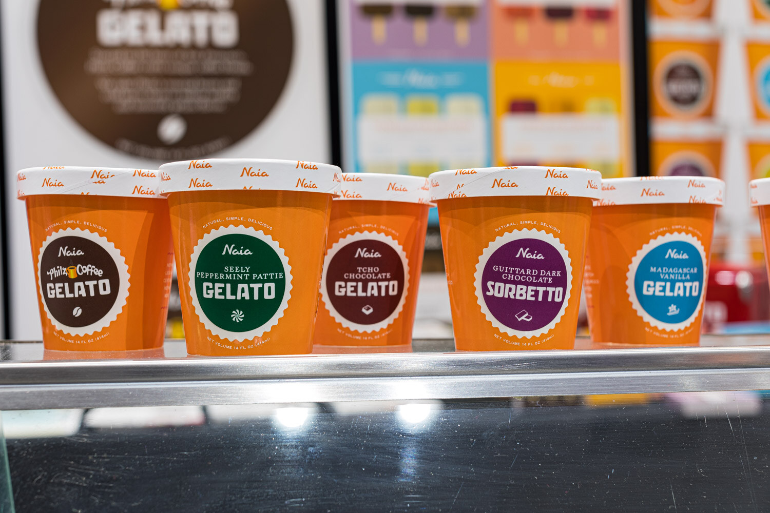 Five orange Naia pints including gelato and sorbetto flavors in a display case