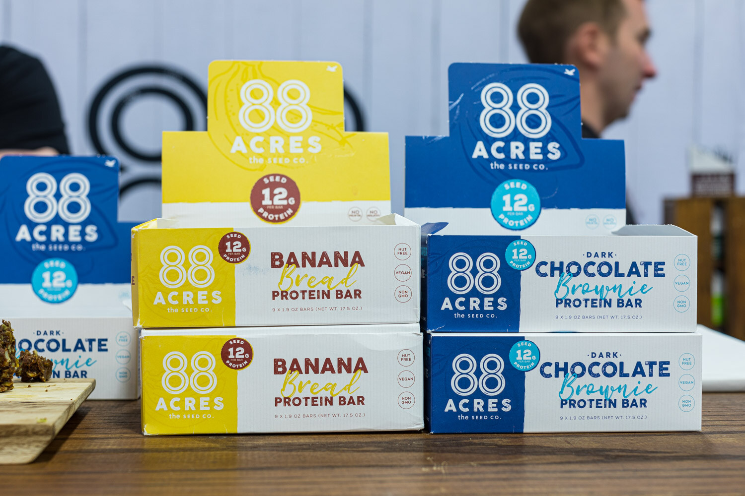 Stacked yellow and blue 88 Acres protein bar boxes in banana bread and dark chocolate brownie flavors