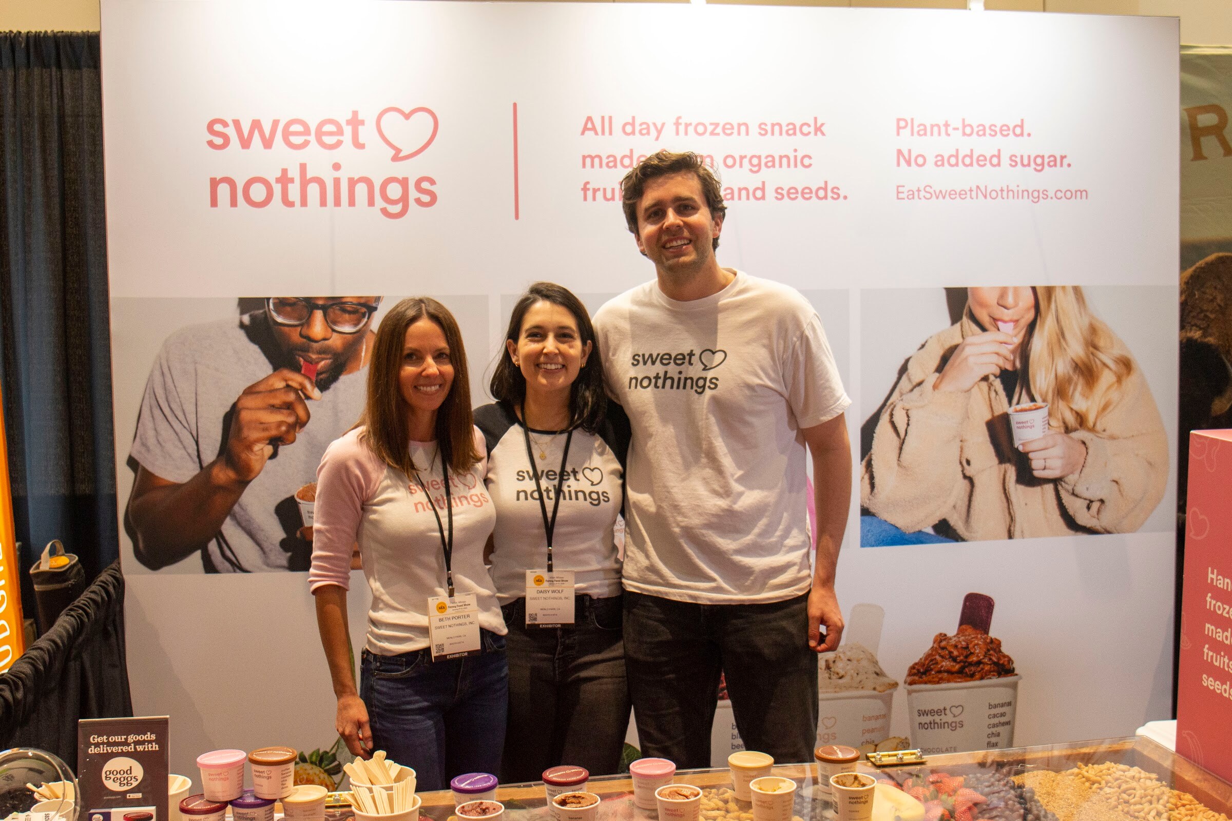 Three people in front of a sweet nothings backdrop with cups of frozen snacks on the counter
