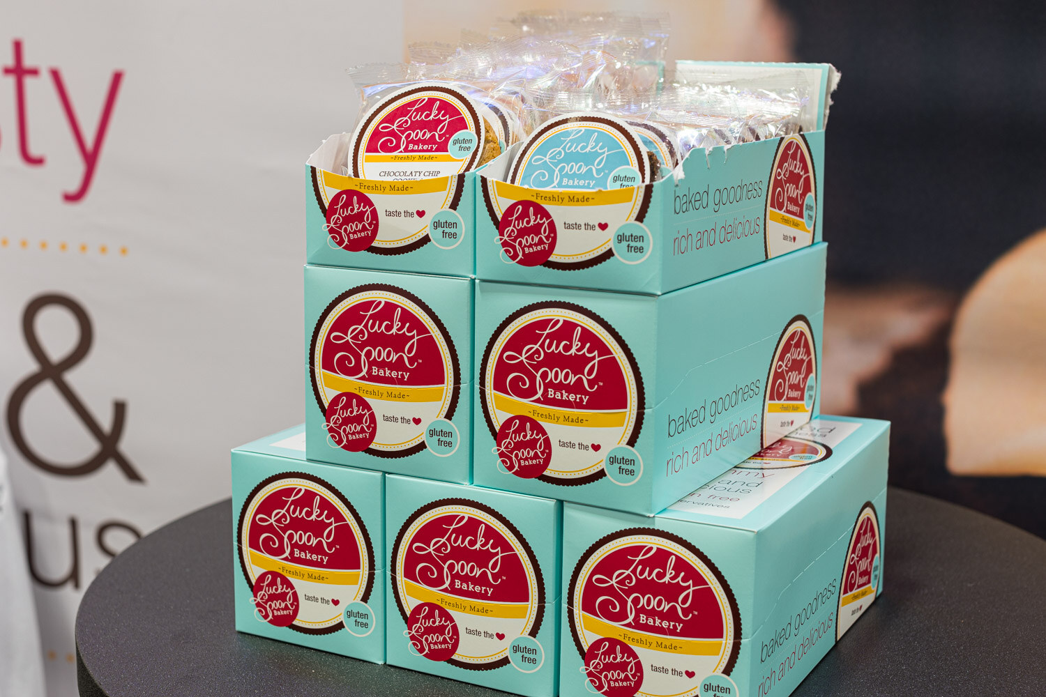 Teal Lucky Spoon Bakery boxes of gluten-free baked goods stacked on a round stand