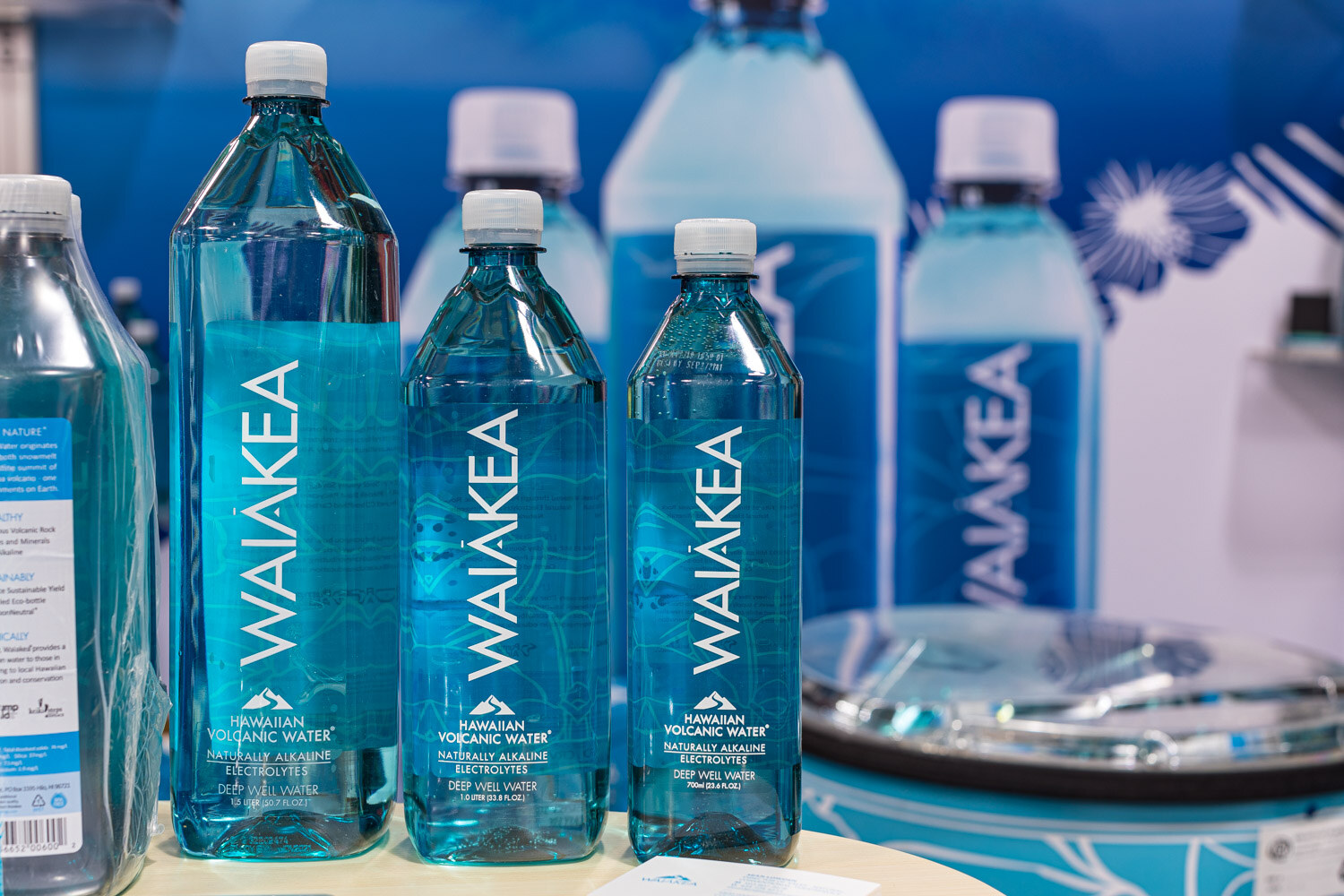 Waiakea Hawaiian Volcanic Water bottles in three sizes against a blue backdrop