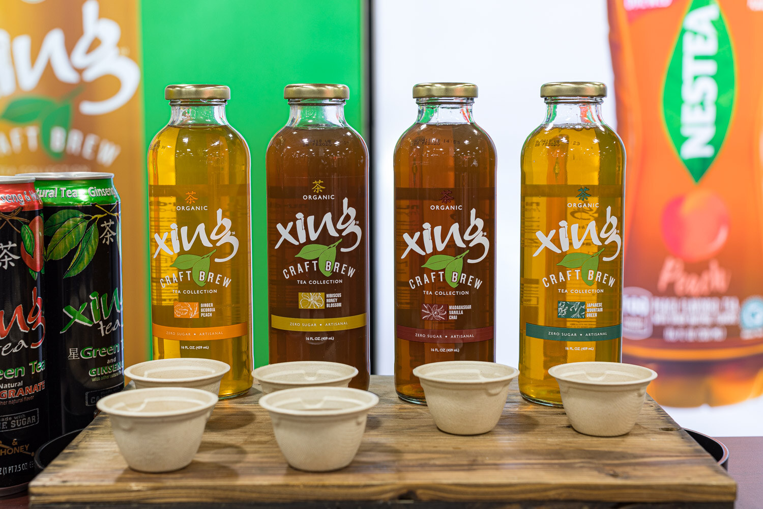 Four Xing Craft Brew tea bottles with small tasting cups in front of them
