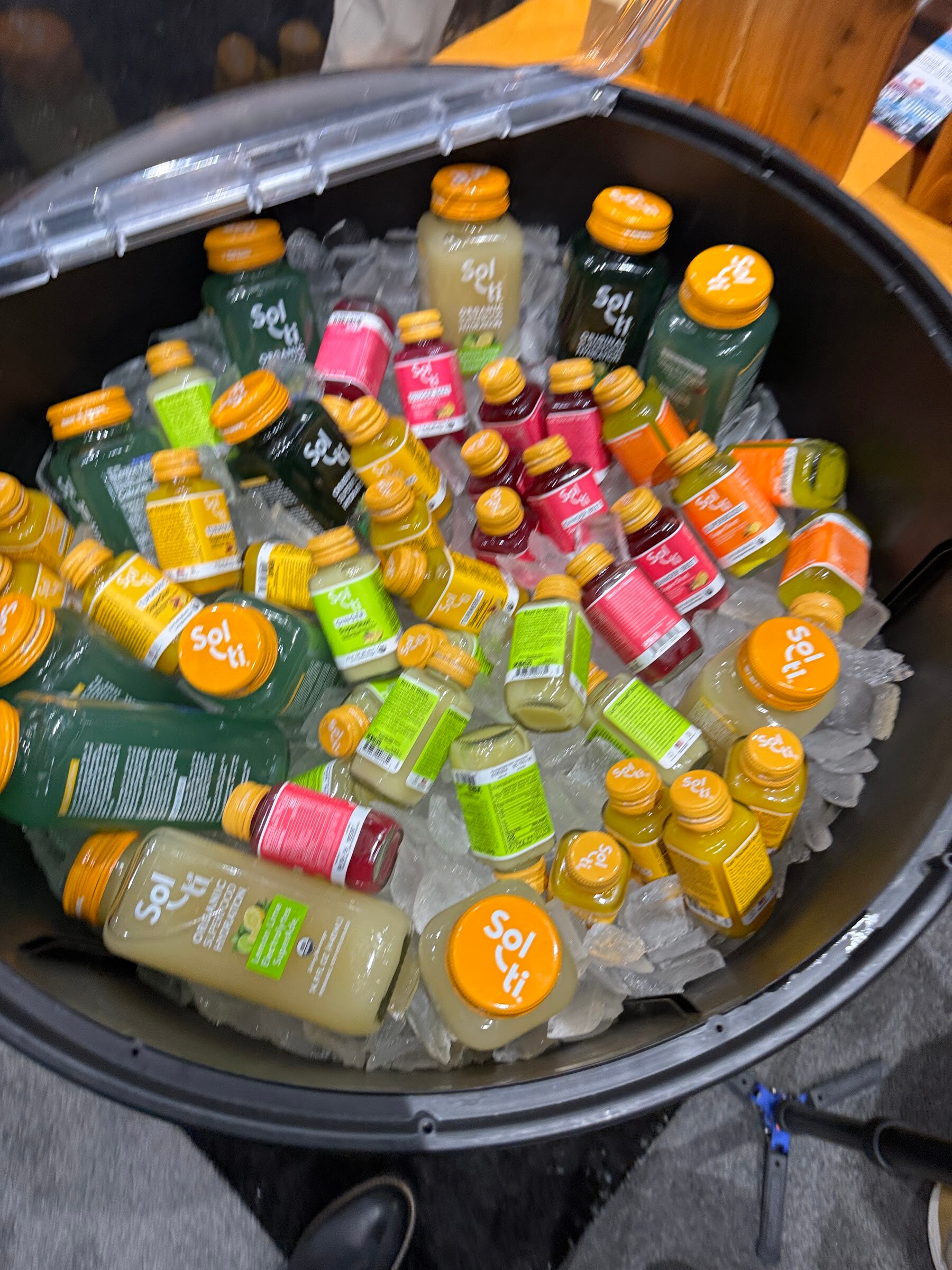 Overhead view of a round cooler filled with ice and Sol-ti bottles in many colors.