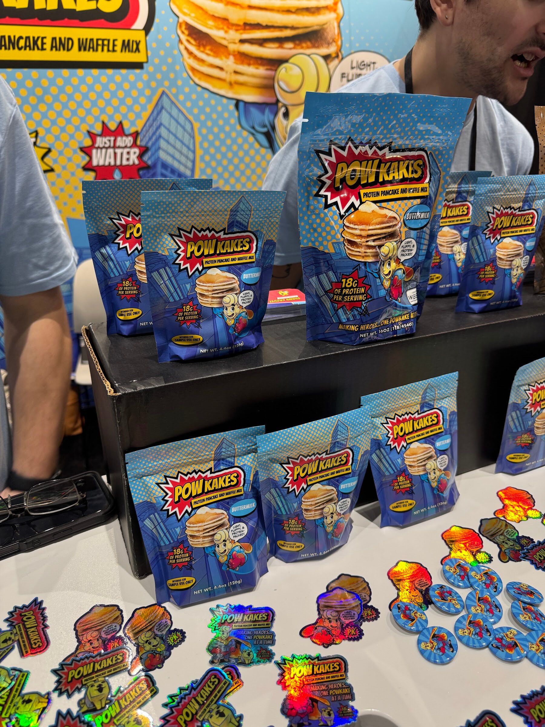 Comic-book style bags of Pow Kakes pancake and waffle mix with holographic stickers on a table.