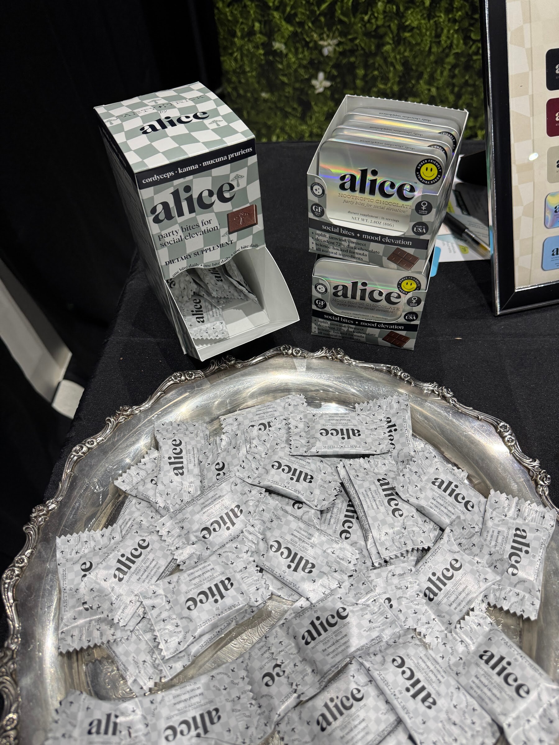 Silver tray piled with individually wrapped alice samples beside alice display boxes.