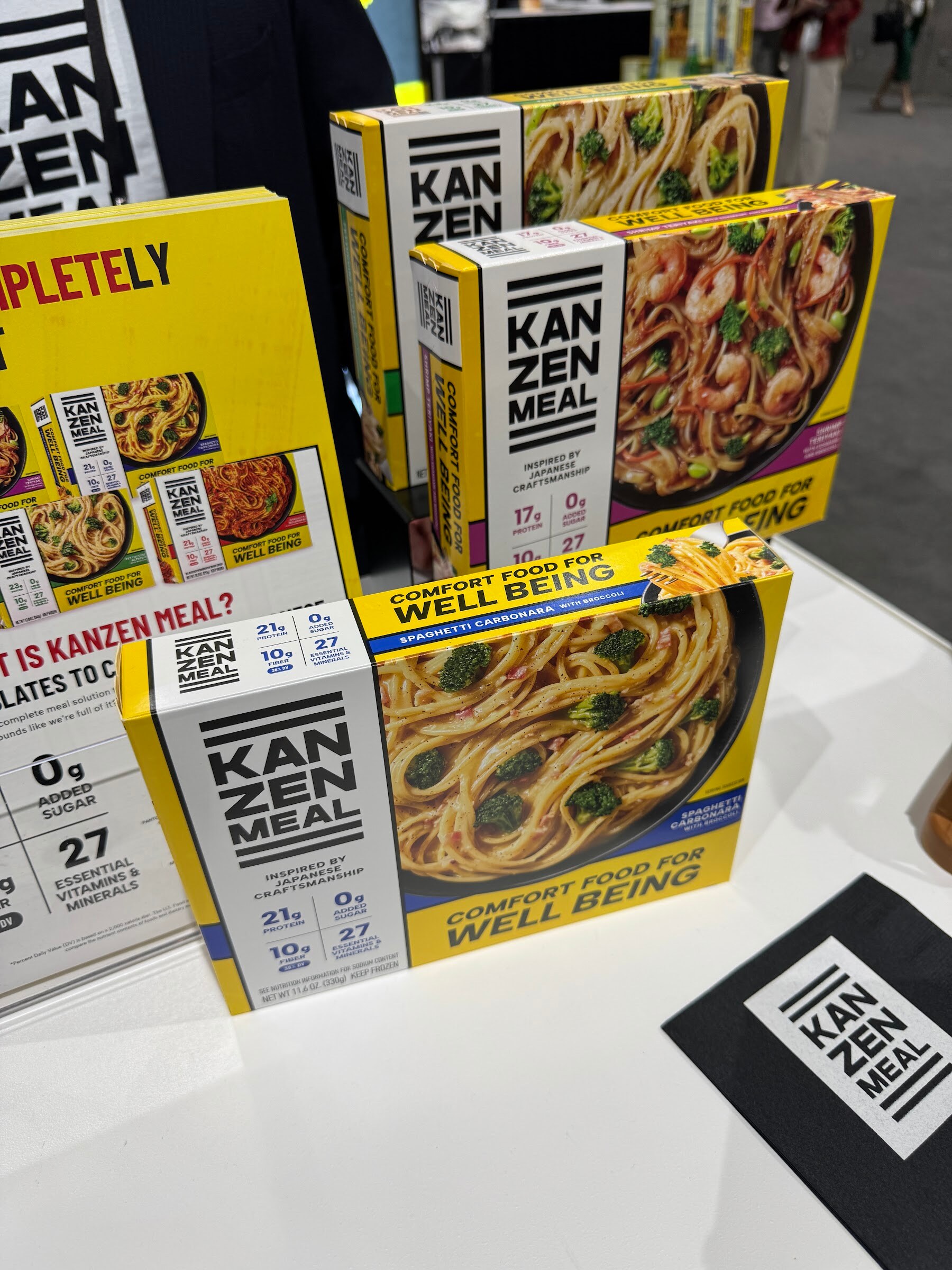Yellow Kanzen Meal boxes reading Comfort food for well being stacked on a white counter.