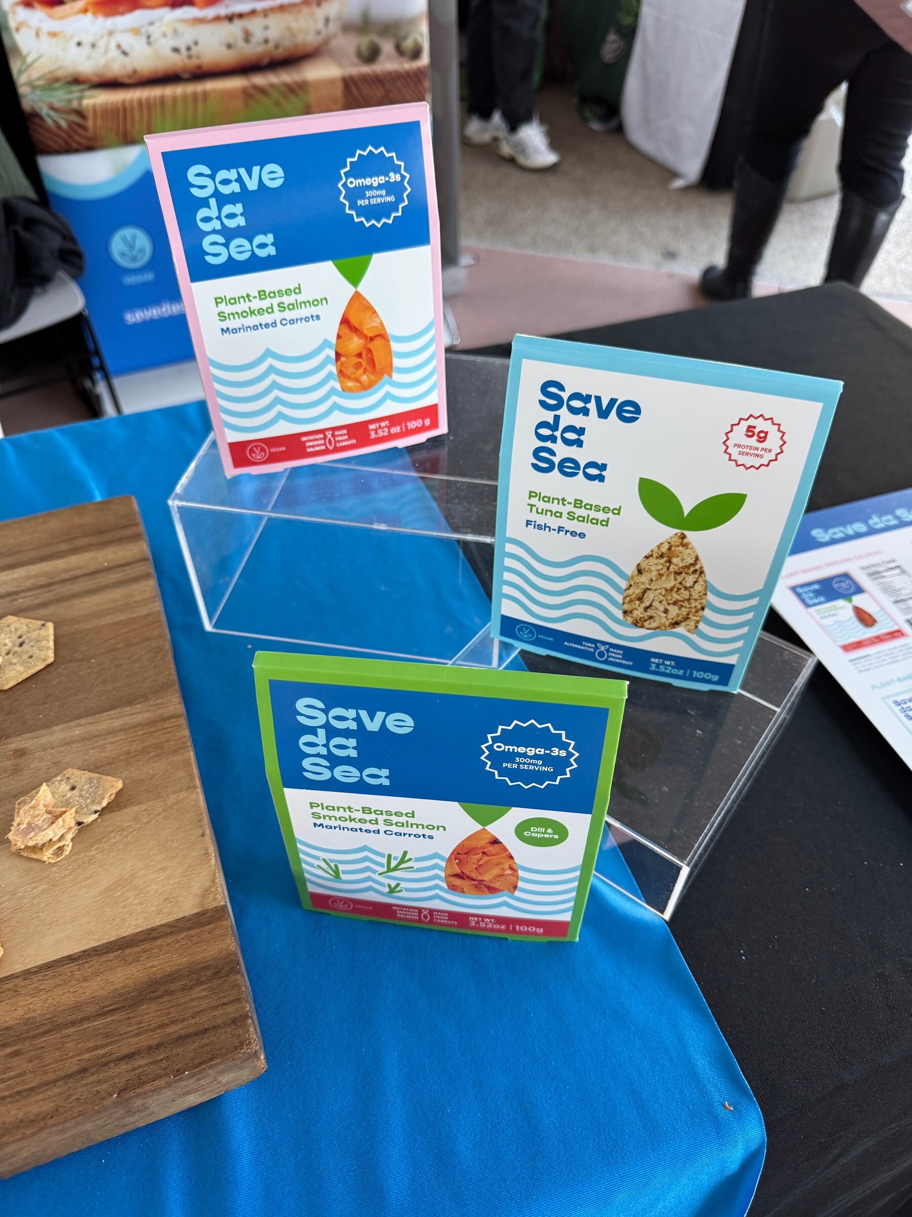 Save da Sea plant-based seafood packages in an acrylic stand on a blue tablecloth.