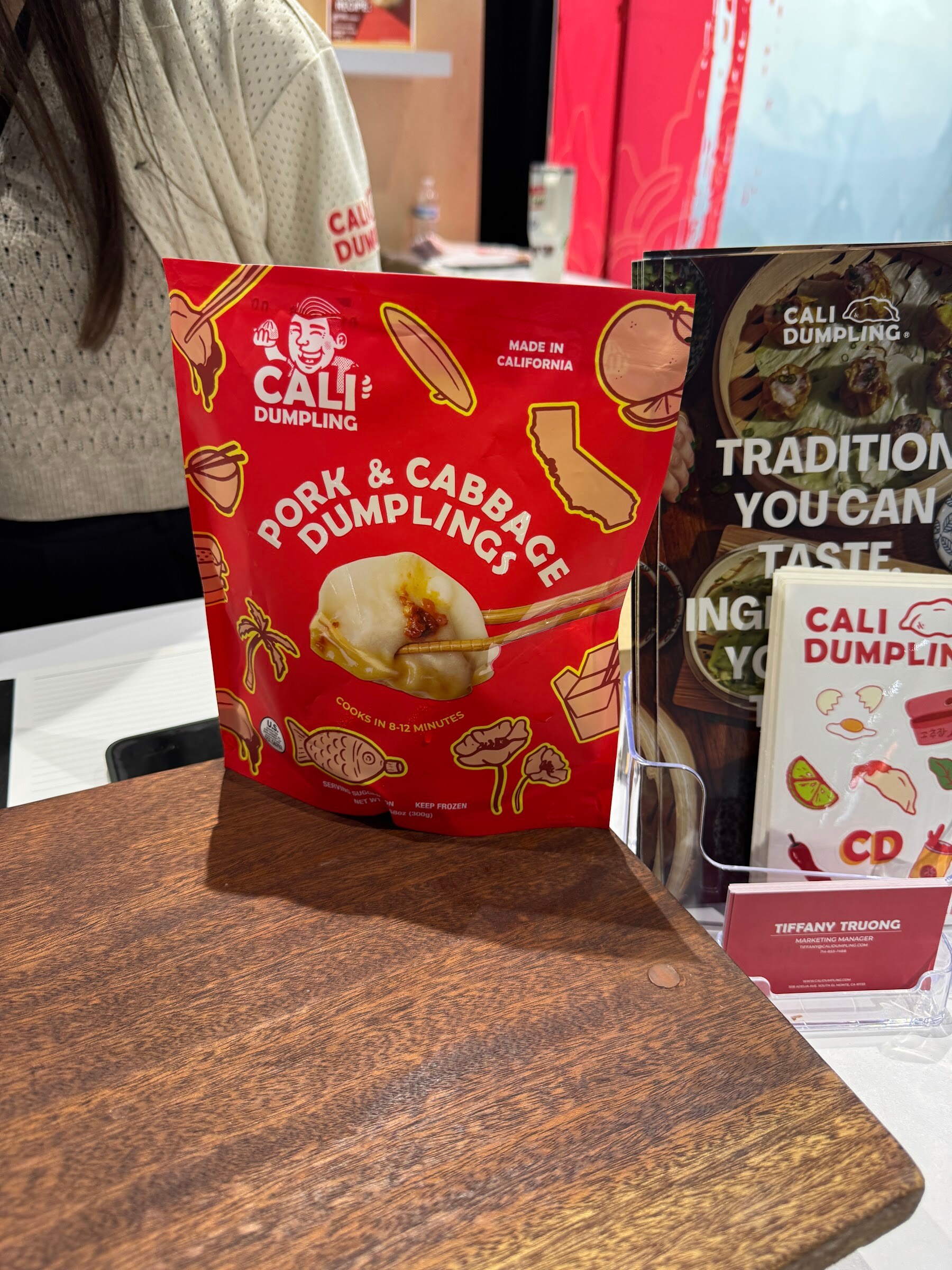 A red bag of Cali Dumpling pork and cabbage dumplings on a wooden board.