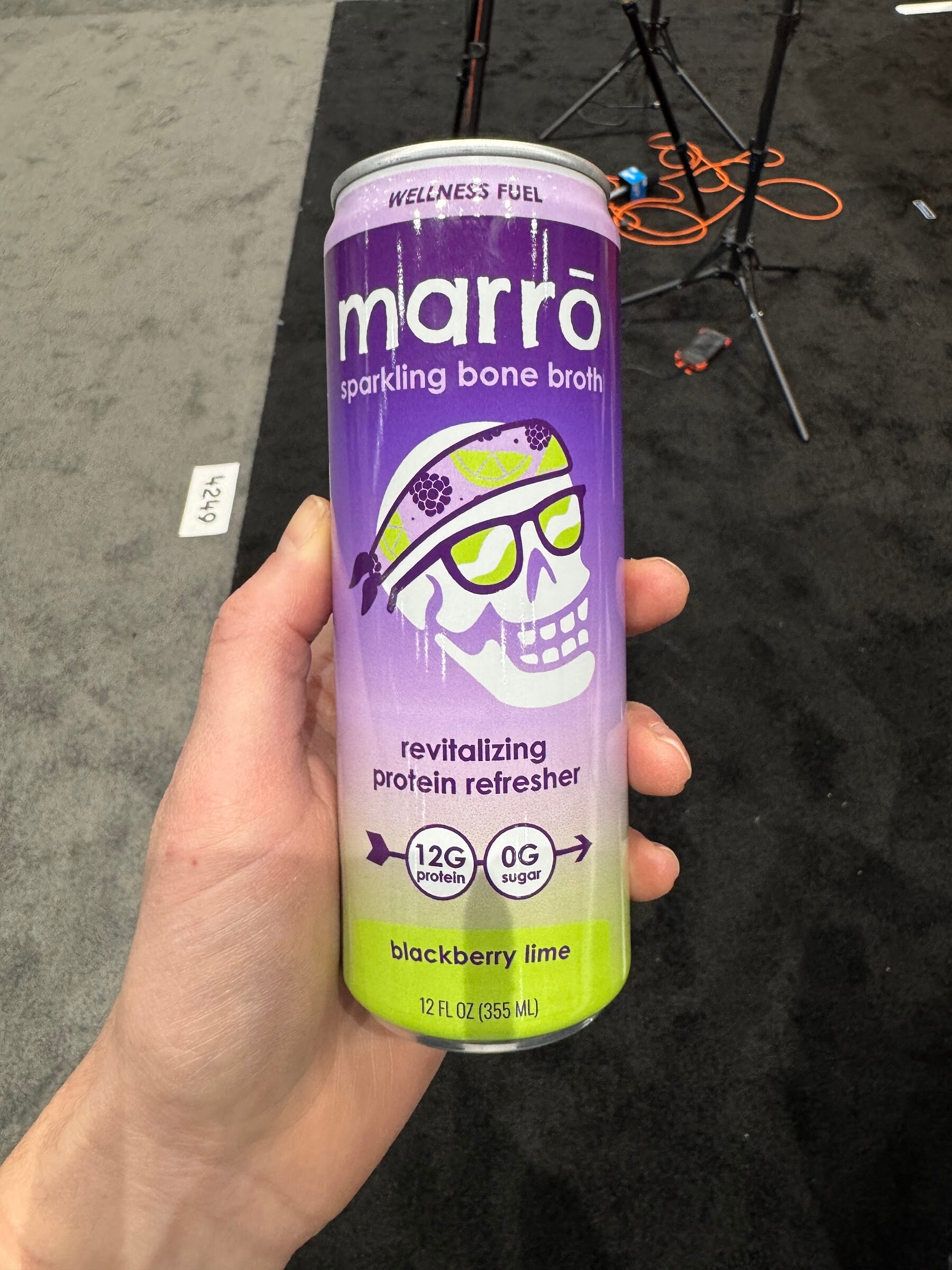 Hand holds a purple and green can of Marro sparkling bone broth in blackberry lime.