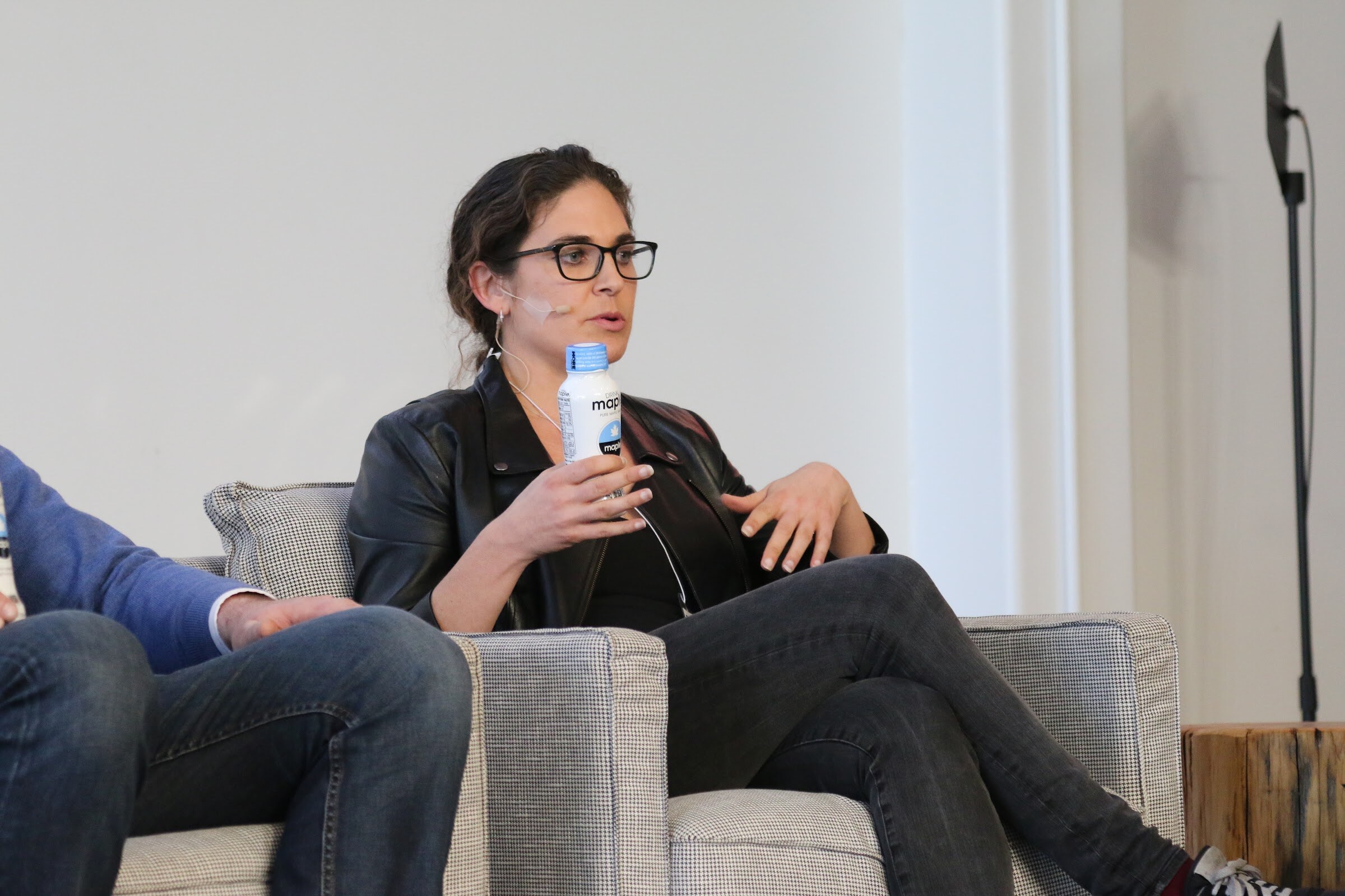 Panelist seated holding Maple bottle, speaking.